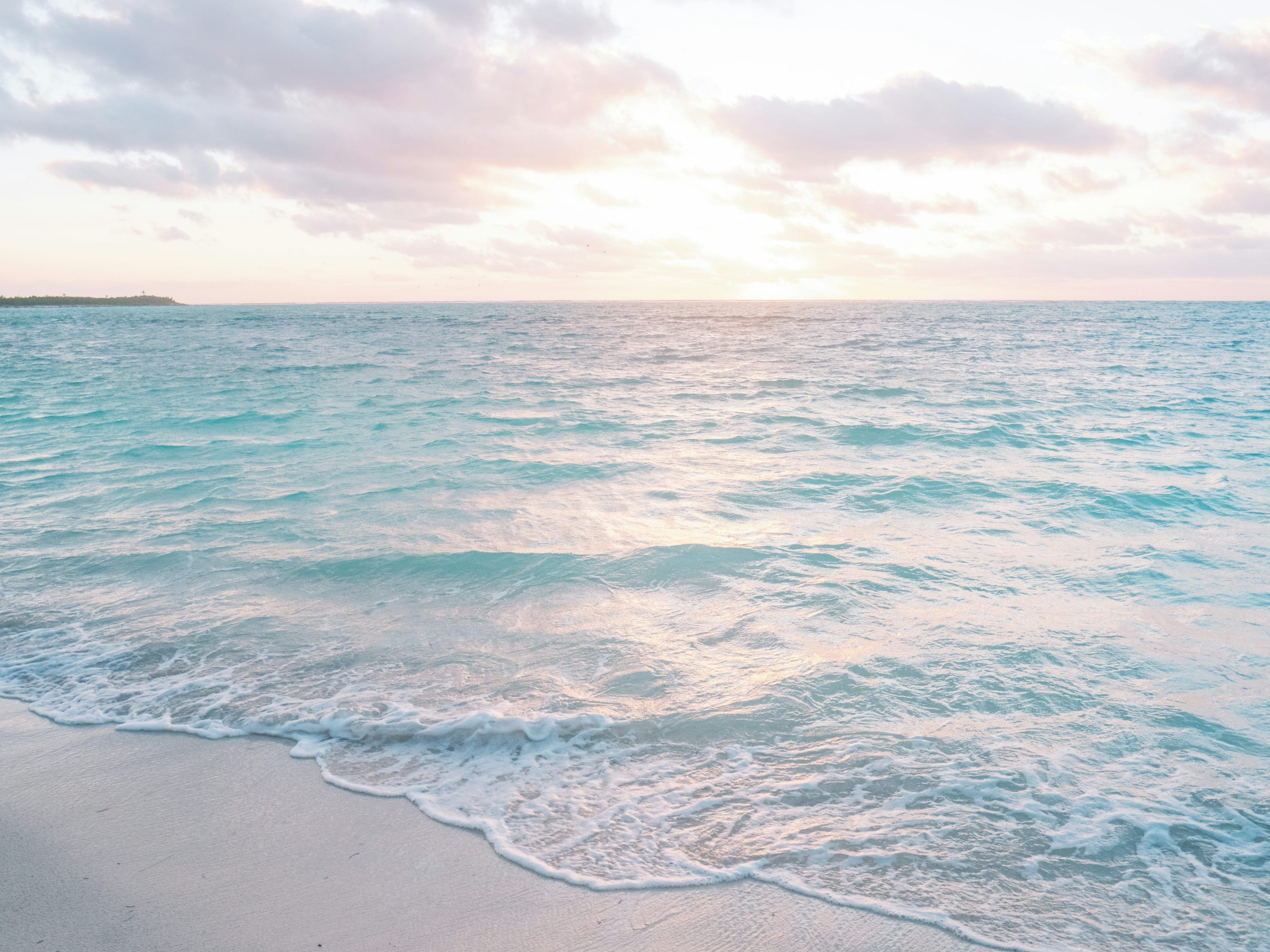 3000x2250 Calm ocean meets a sandy beach under a pastel sky. photo