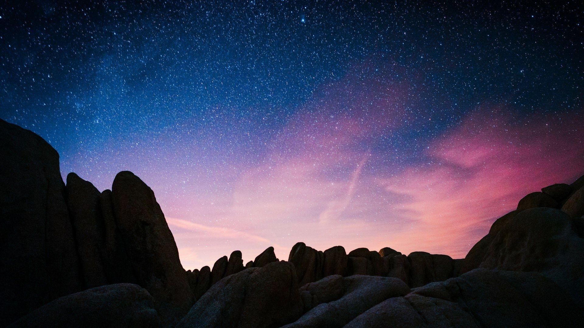 1920x1080 The sky full of stars with blue and pink hues over the rock formations