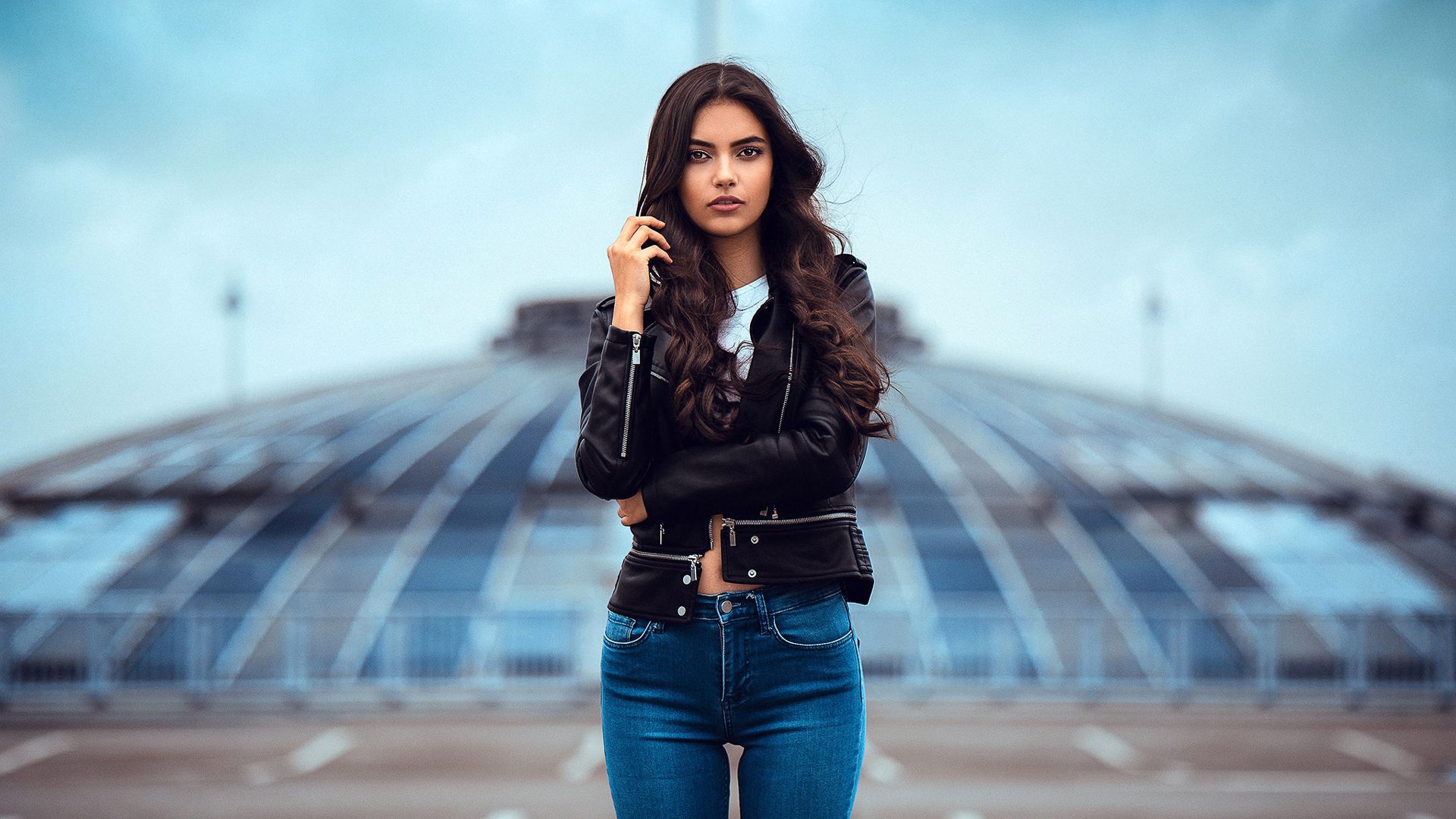1920x1080 Beautiful Laura Theresa Girl Model Is Posing For A Photo Standing In Blur Background Wearing Black Leather Jacket And Blue Jeans HD Girls Wallpaper