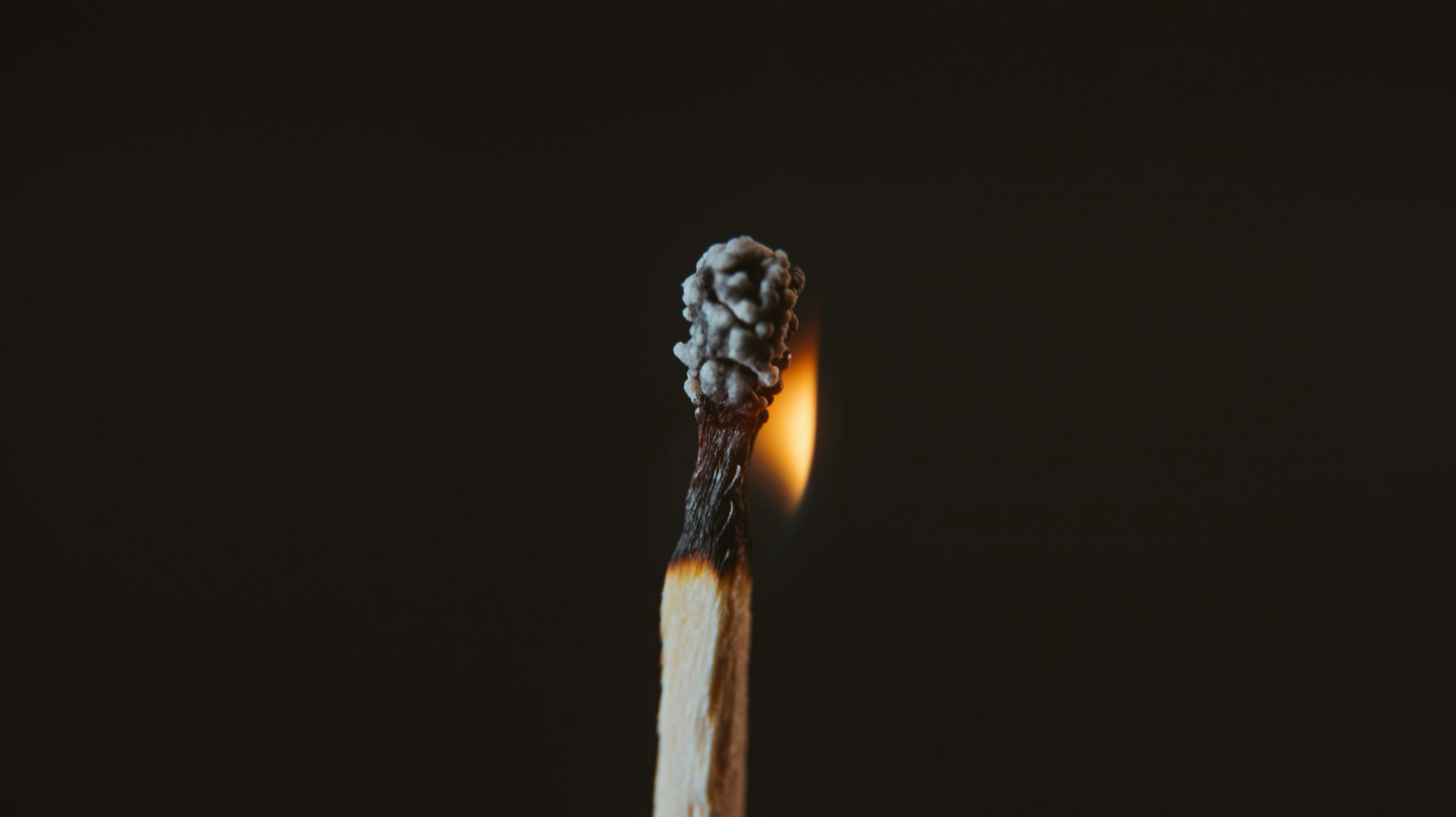 3000x1685 A lit matchstick with a black background photo