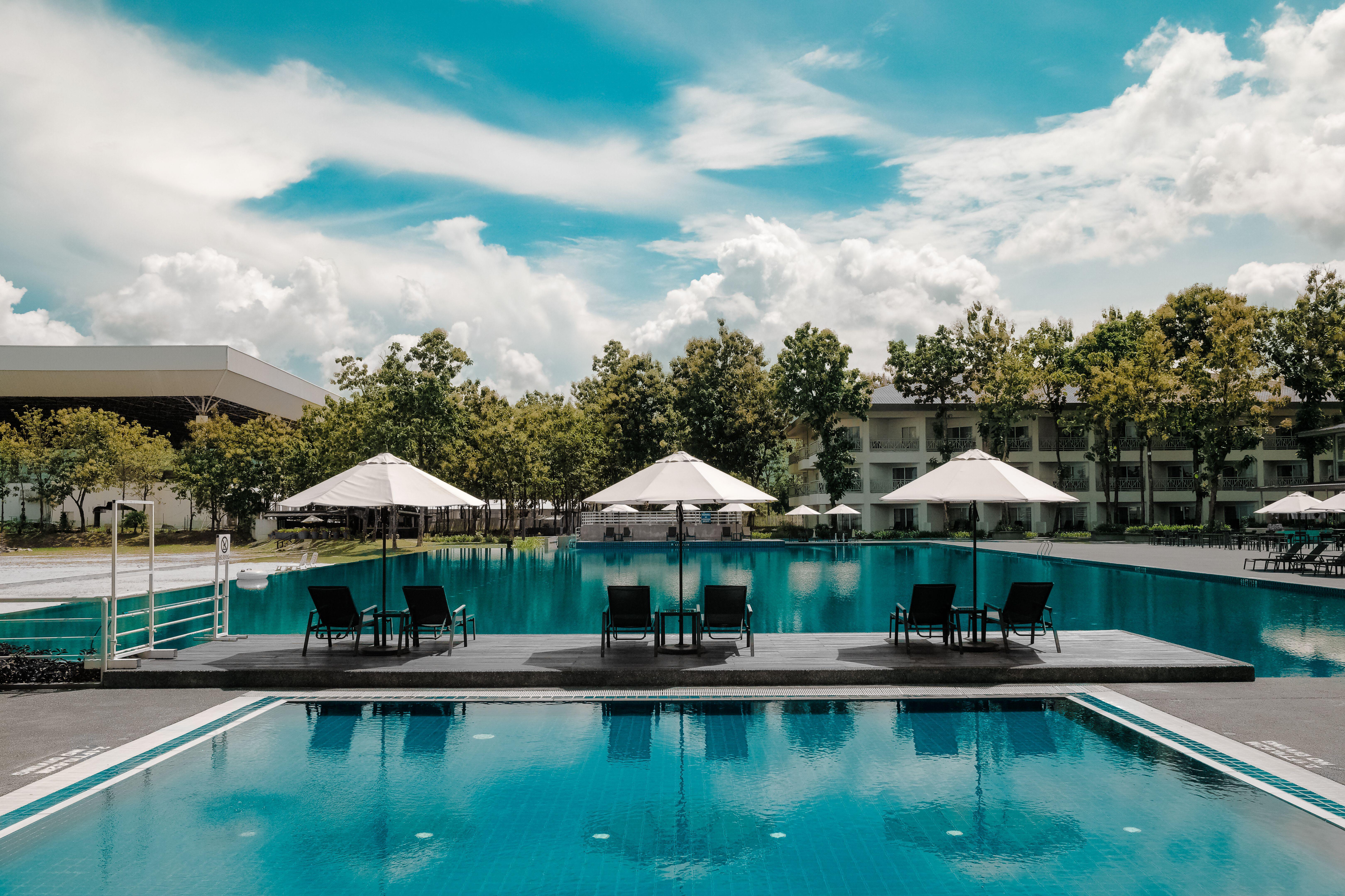 6480x4320 Black Outdoor Lounge Chair in Between Blue Swimming Pool Under White Cloudy Blue Sky · Free