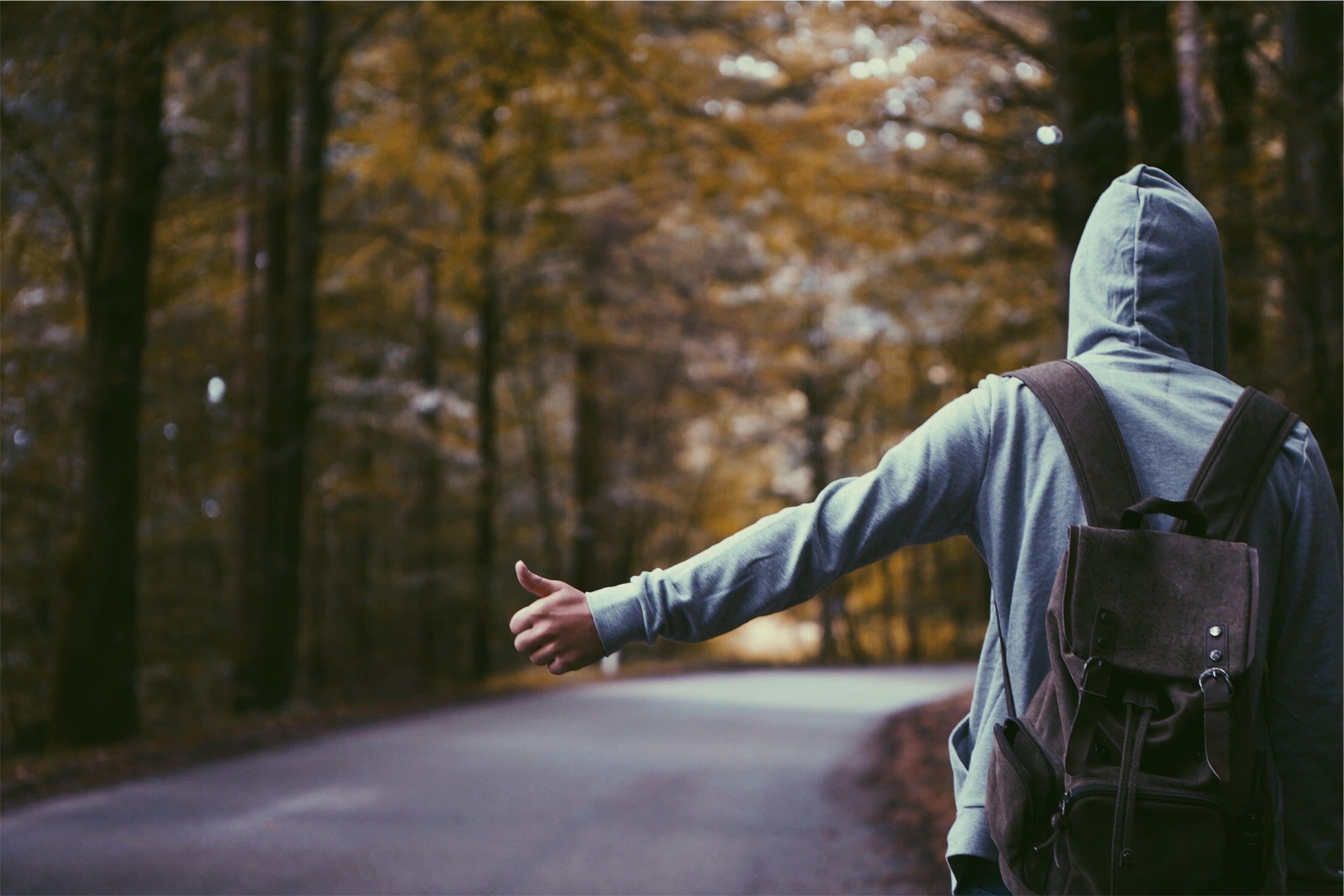 2509x1673 Person in gray hoodie wearing backpack standing on asphalt