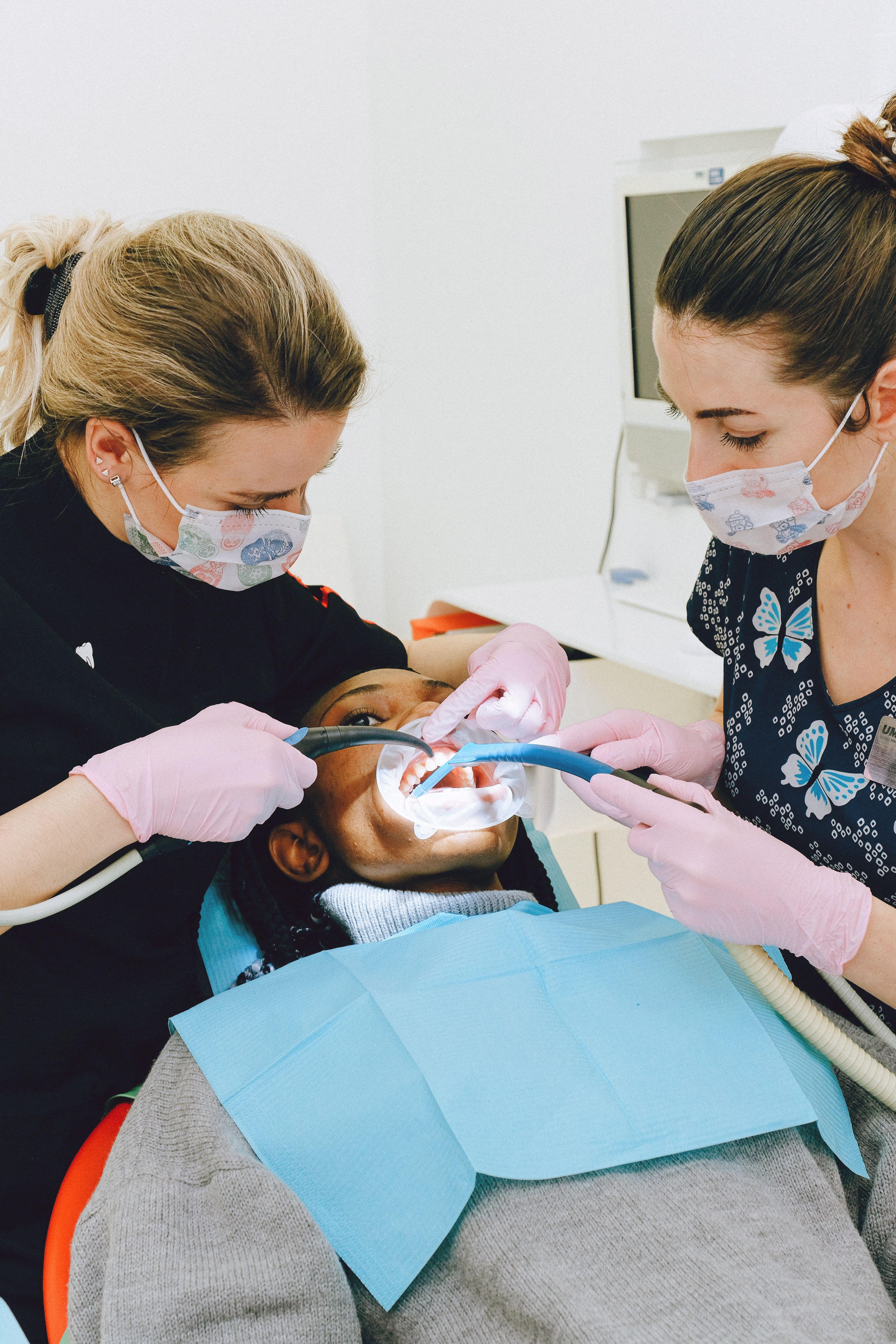 4000x6000 Female dentist with assistant treating patient in clinic · Free
