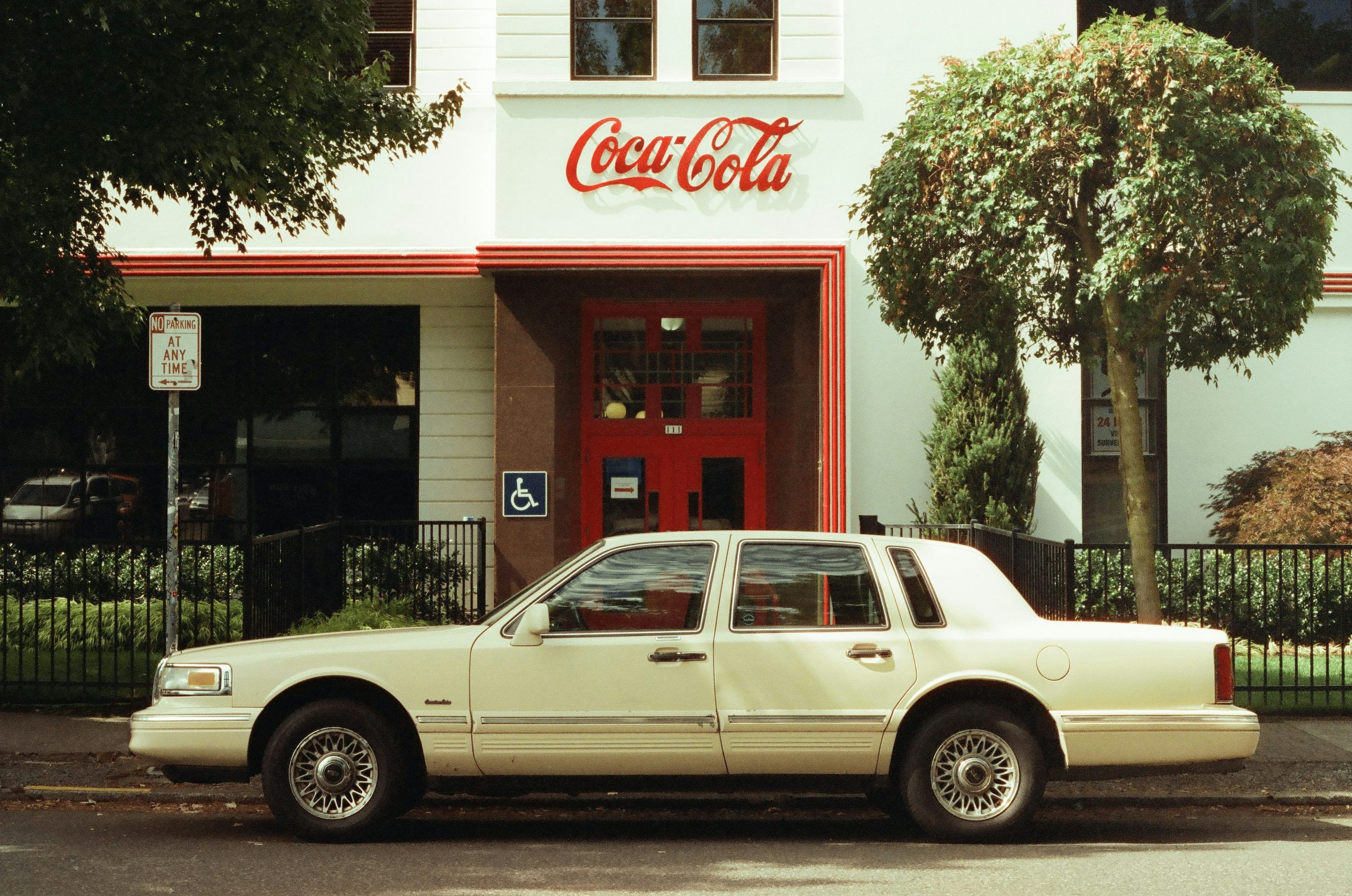 3000x1989 A white car parked in front of a coca cola store photo