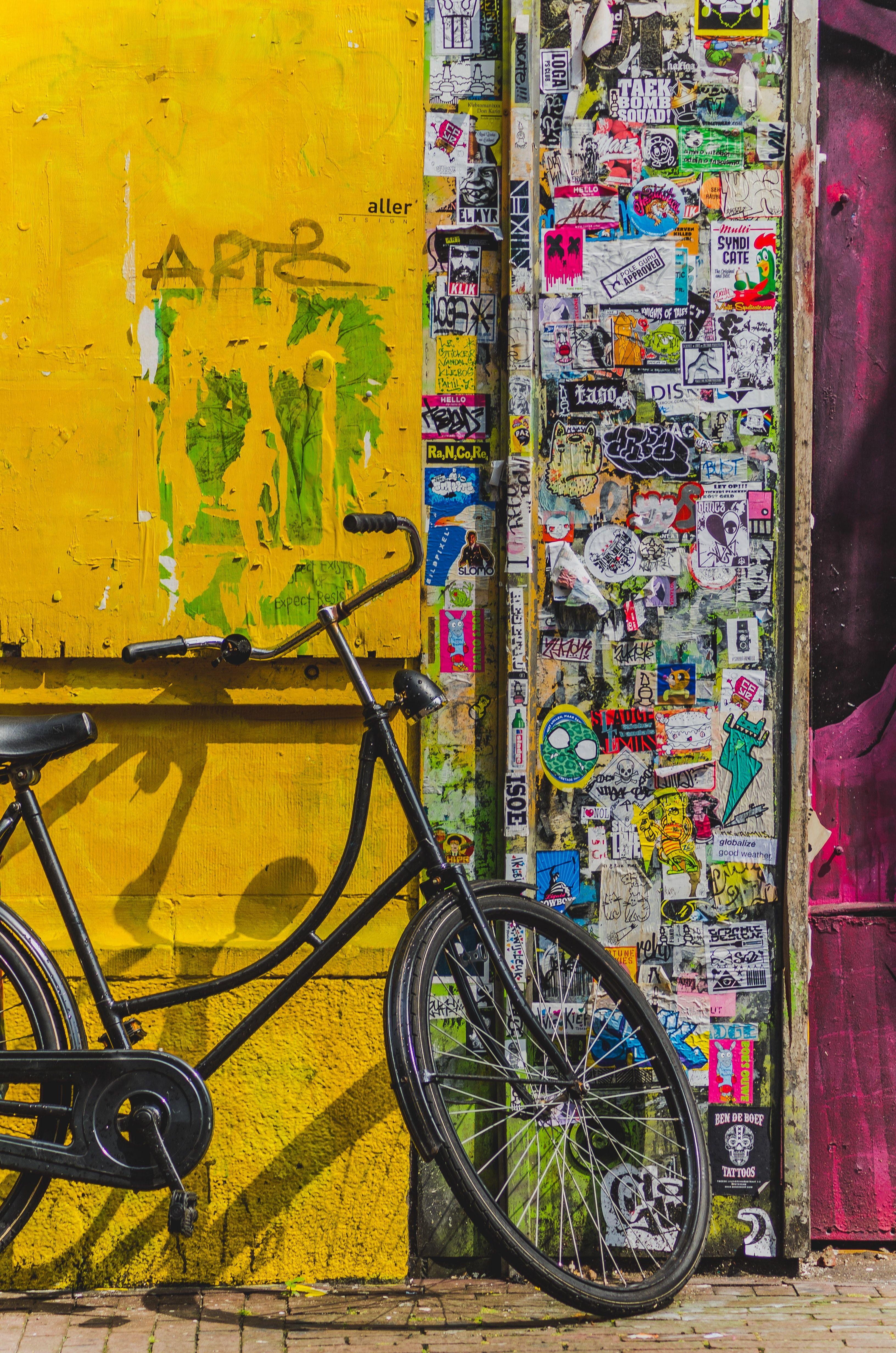 3264x4928 bike parked beside wall full of stickers photo