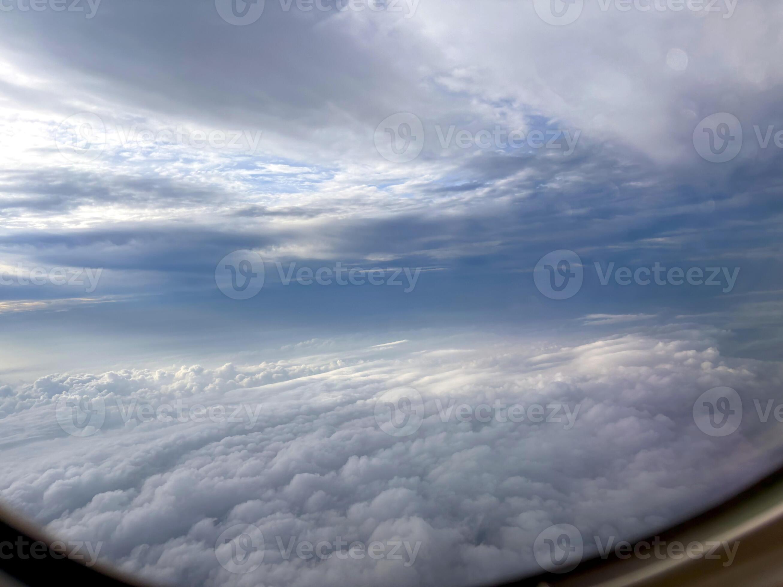 2613x1960 Looking out from an airplane above a swirling sea of clouds and a radiant sky. An atmospheric airplane view above dense clouds. Scenic or business flight travel photo. Nature background. 68572212 Stock
