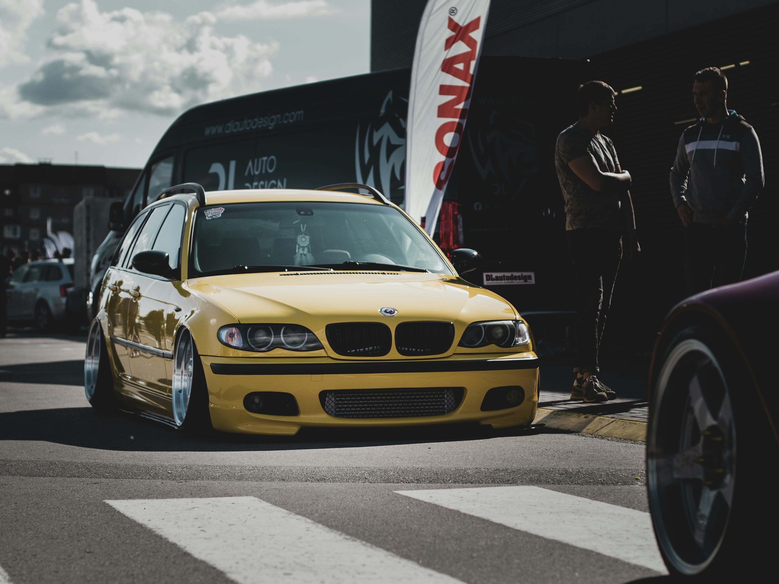 3000x2250 A yellow car with a person standing on the side of it photo