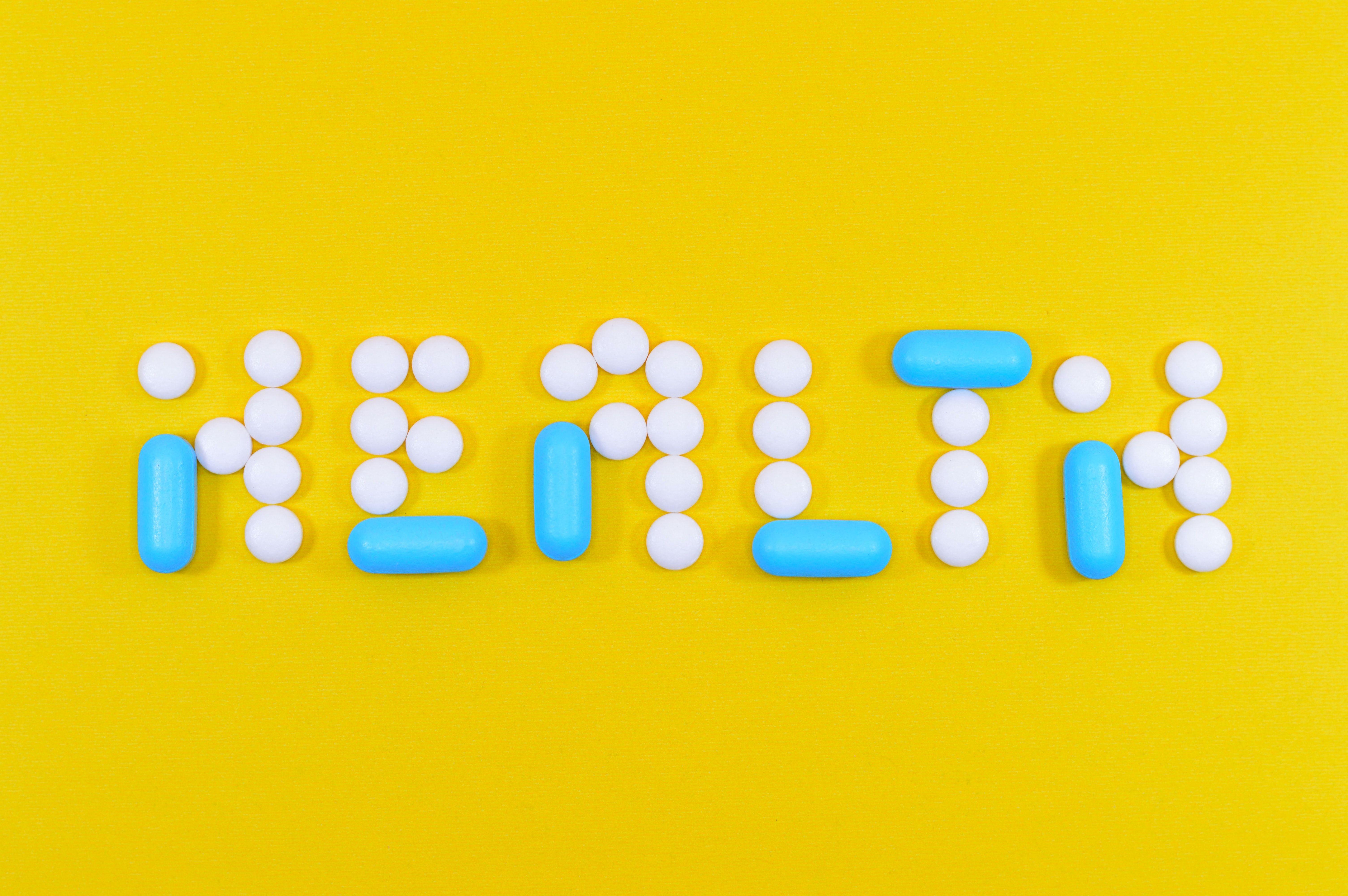 6016x4000 White and Blue Health Pill and Tablet Letter Cutout on Yellow Surface · Free