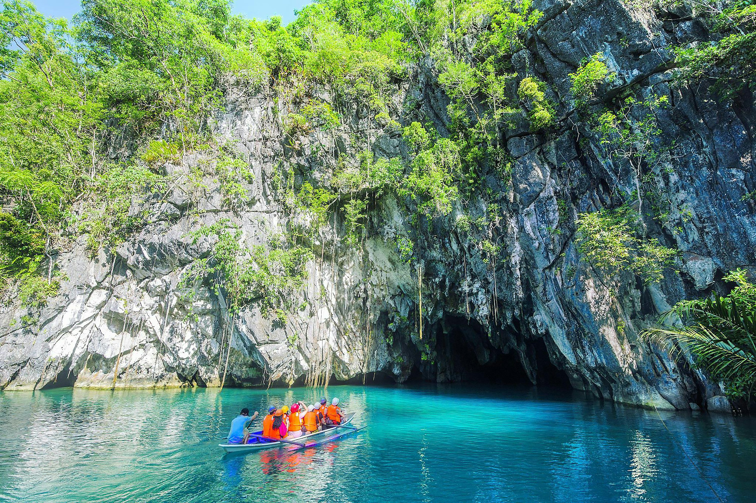 3000x1996 A group of people in a boat in a body of water by a cliff with Puerto Princesa Subterranean River National Park in the background photo