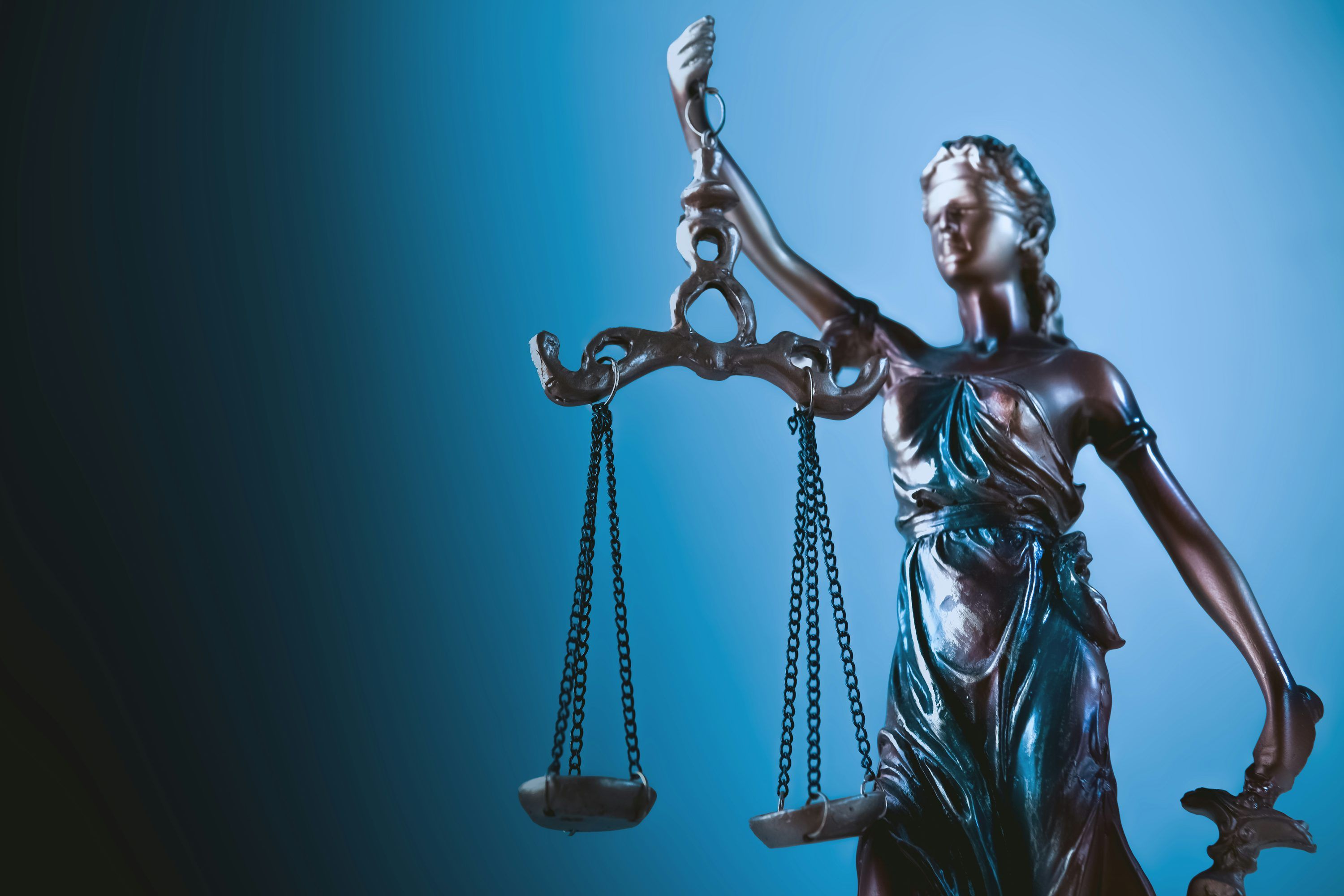3000x2000 Statue of justice holding scales against blue background photo