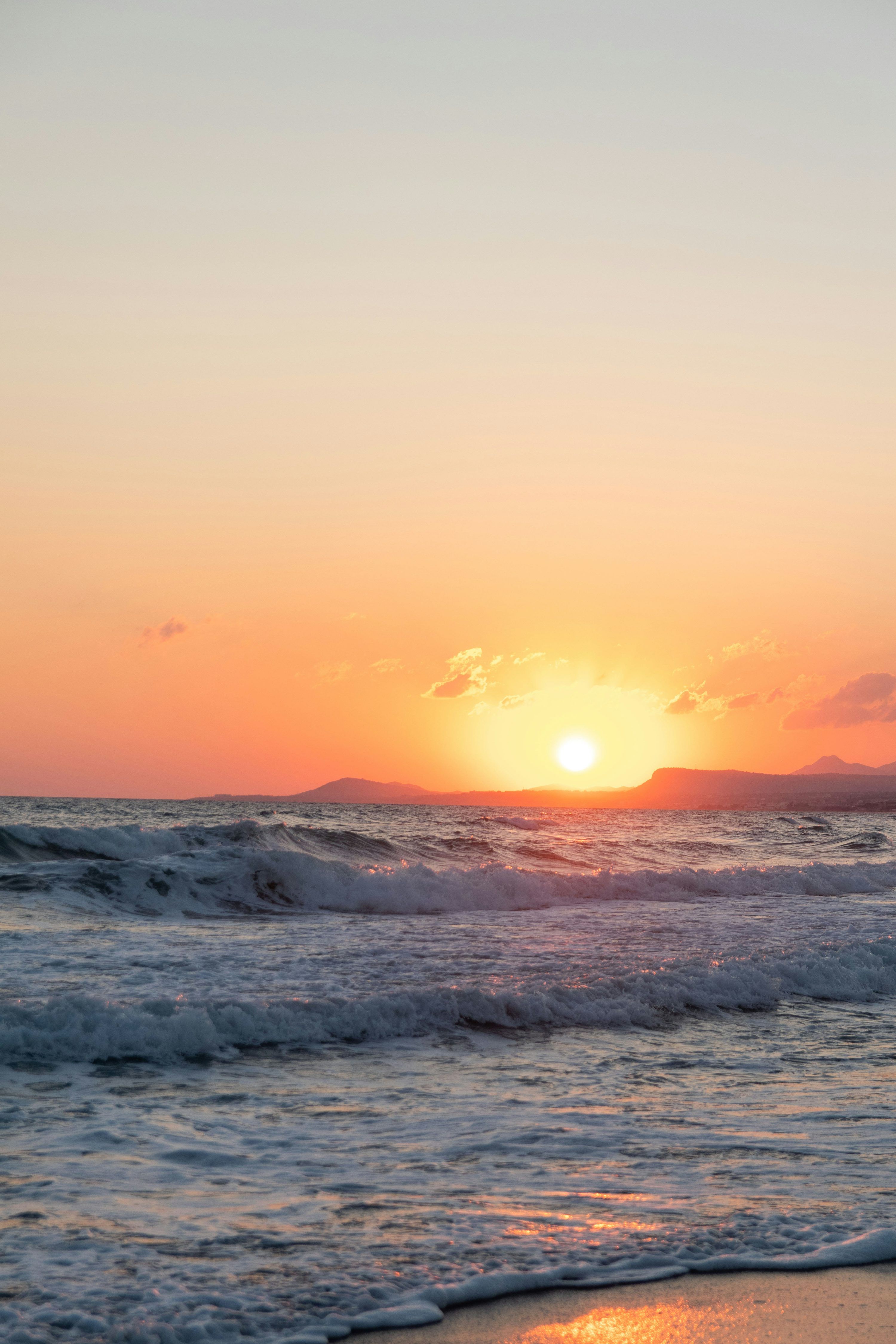 3000x4500 The sun is setting over the ocean on the beach photo