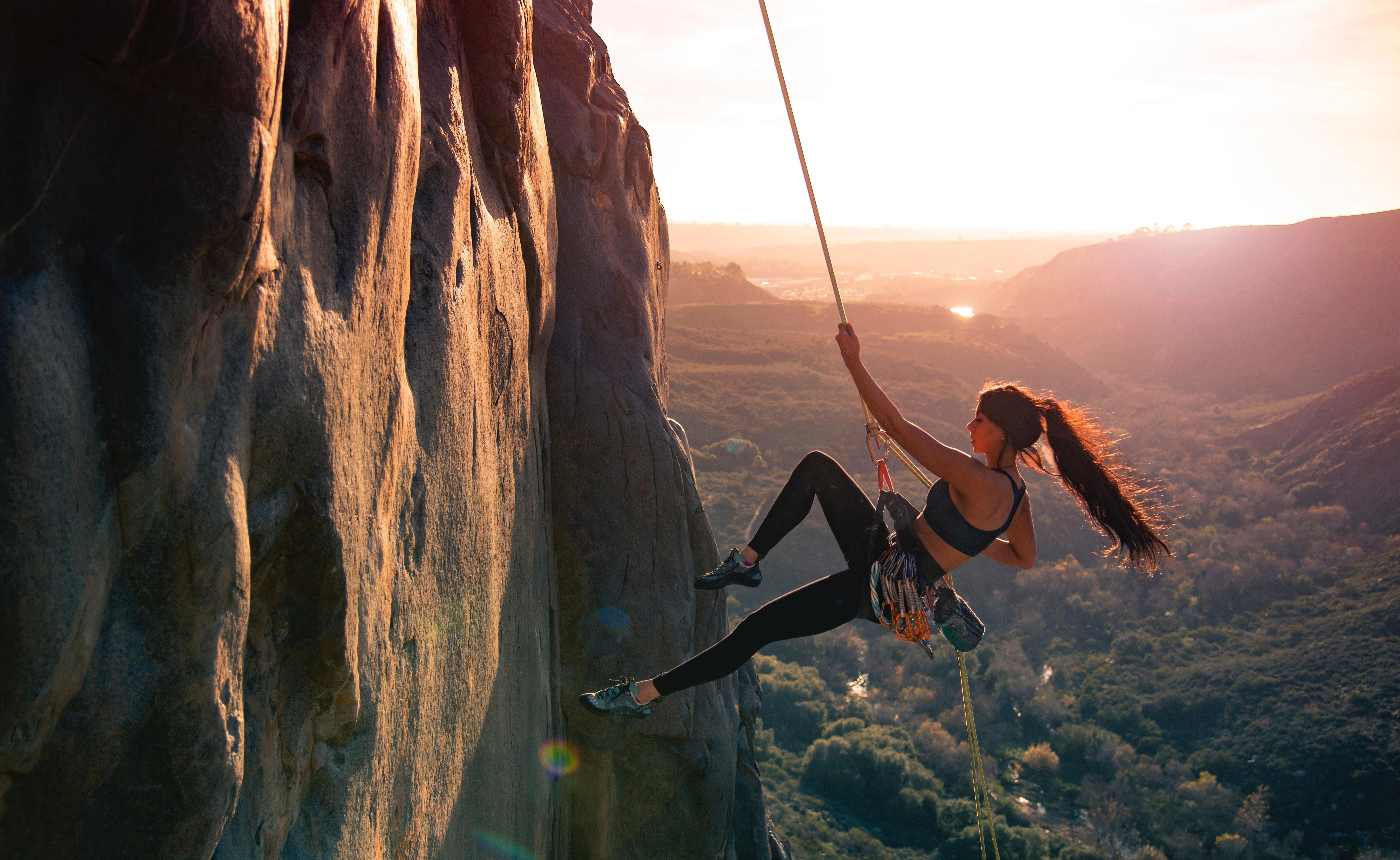 6016x3697 Wallpaper Woman in Black Tank Top and Black Pants Climbing on Brown Rock Formation During Daytime, Background Free Image