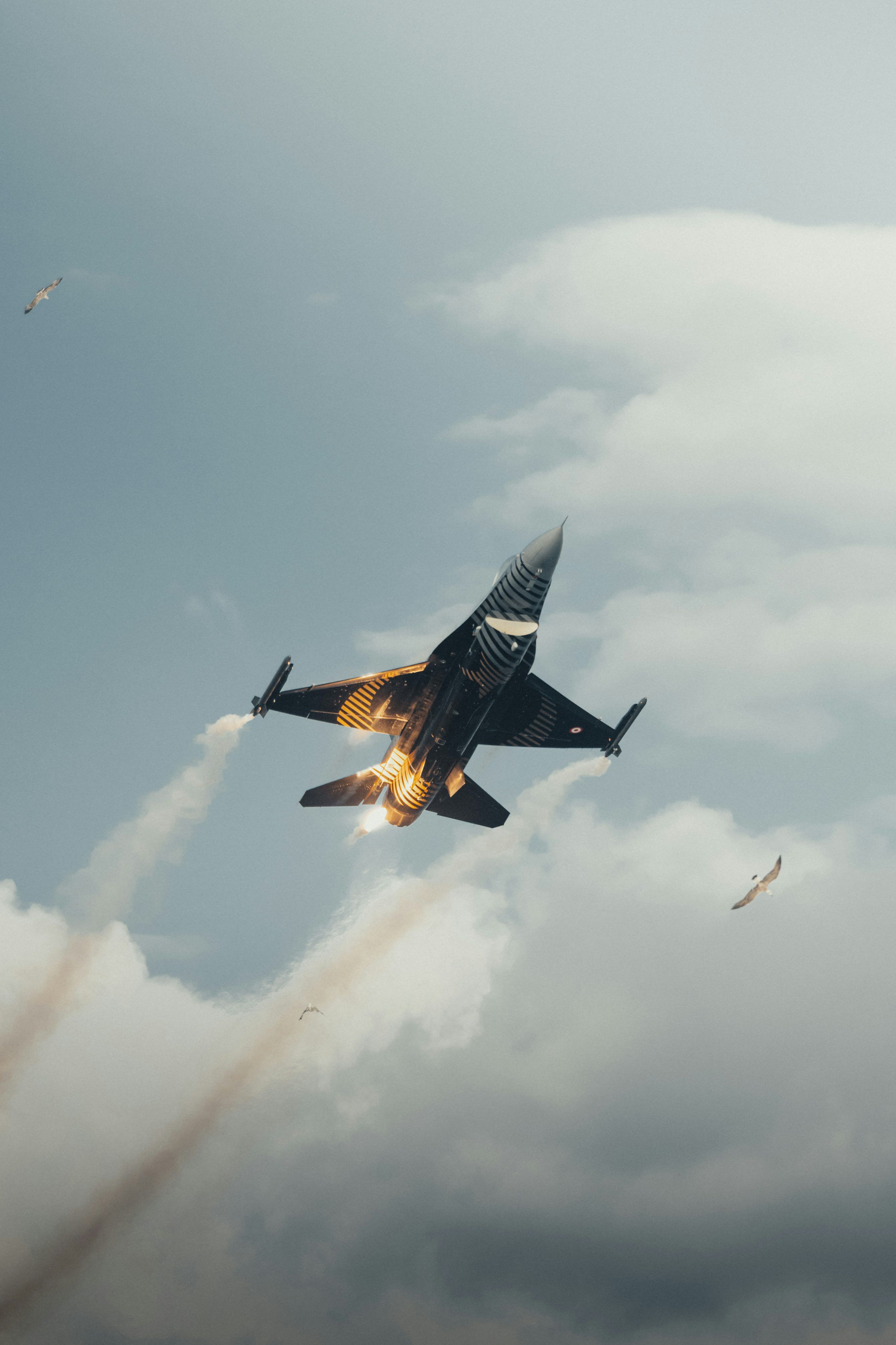 3000x4500 A fighter jet flying through a cloudy blue sky photo