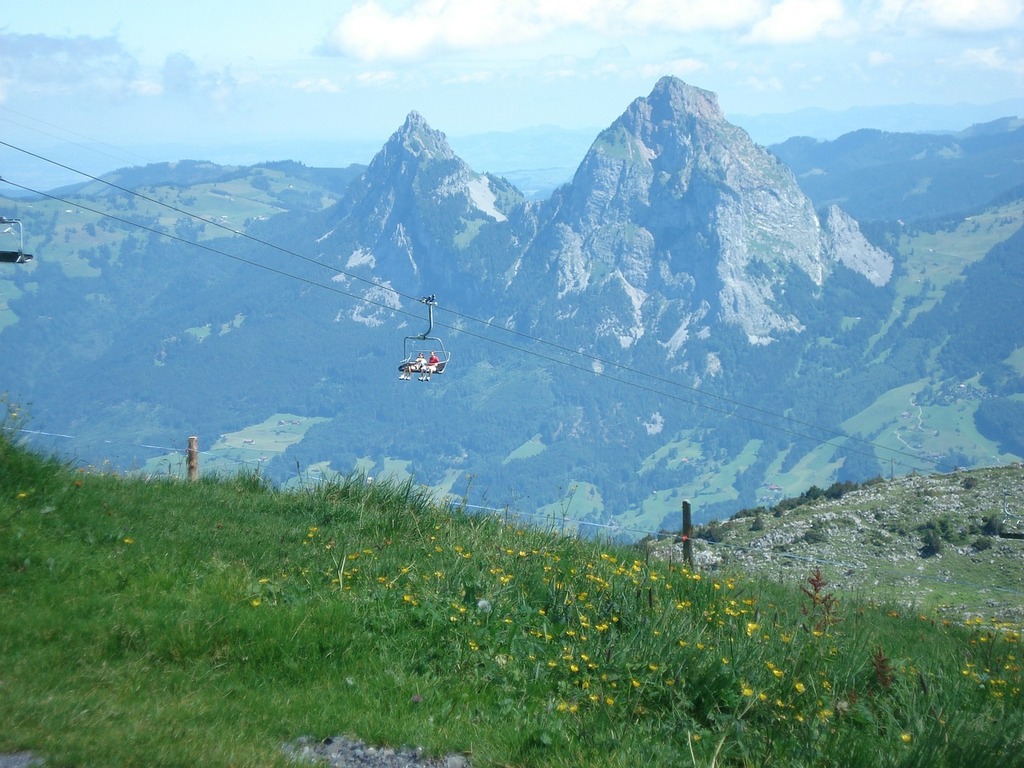 1024x768 A helicopter flying over a lush green hillside. Schwyz