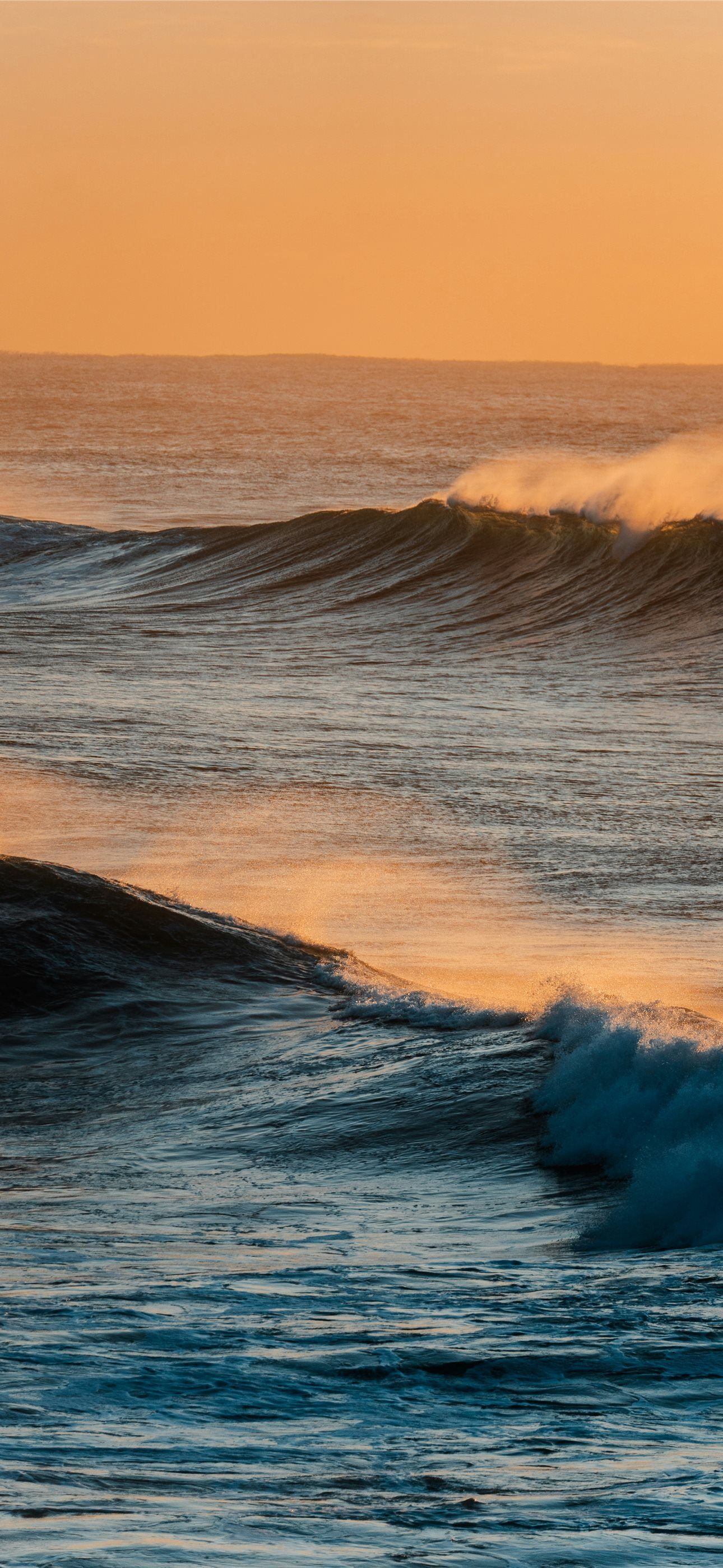 1290x2796 Ocean waves at sunset with warm orange sky iPhone Wallpaper Free Download
