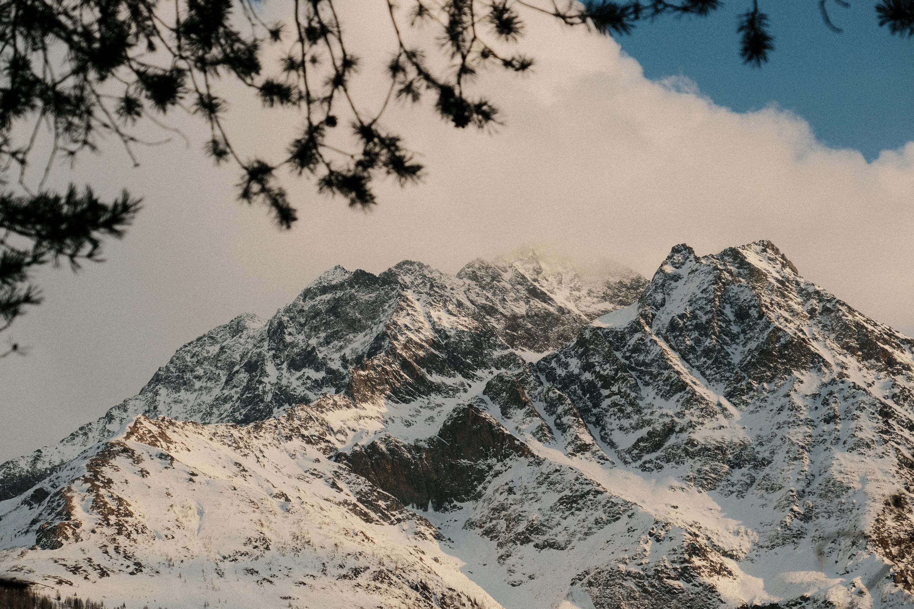 3000x2000 Snow covered mountain peaks under a cloudy sky photo