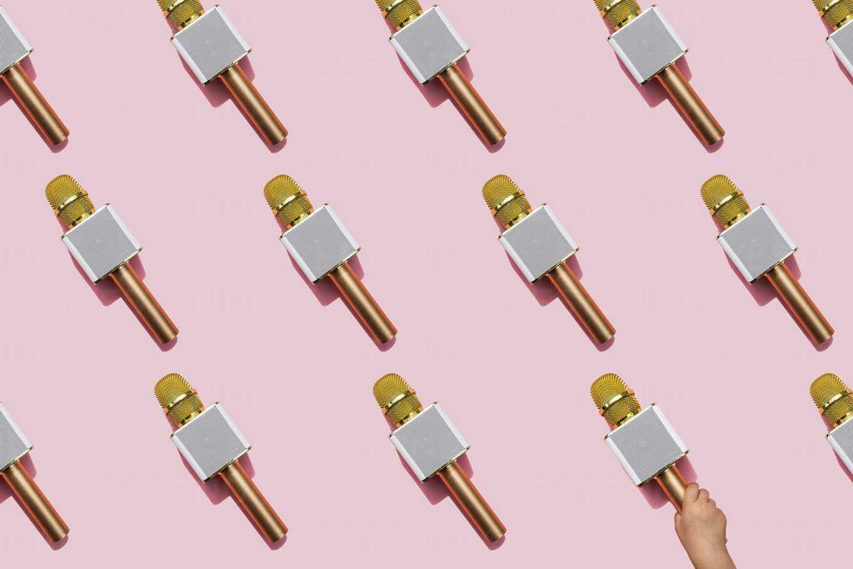 1232x822 Pattern of golden microphones against pink background with hand of baby girl picking one up