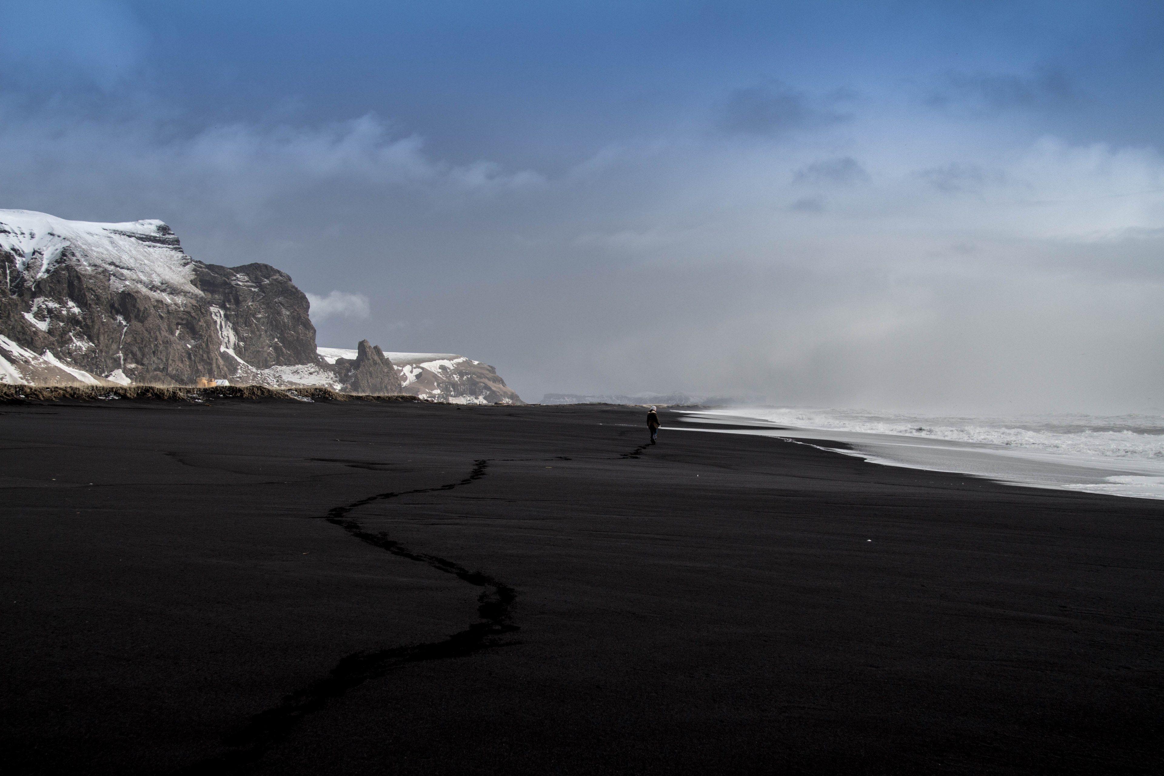 3840x2560 Wallpaper / person walks alone on a volcanic beach in a mountain landscape, lonely beach walk 4k wallpaper