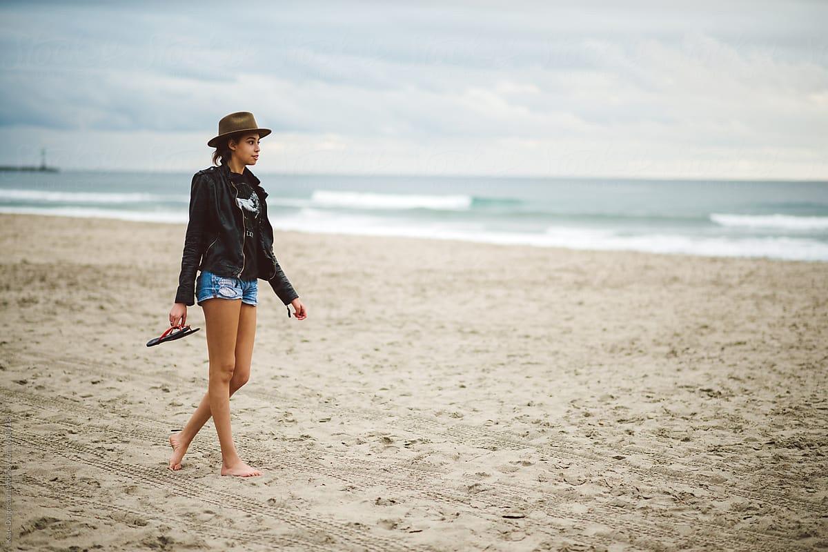 1200x800 Beautiful young woman walking down beach alone at sunset.