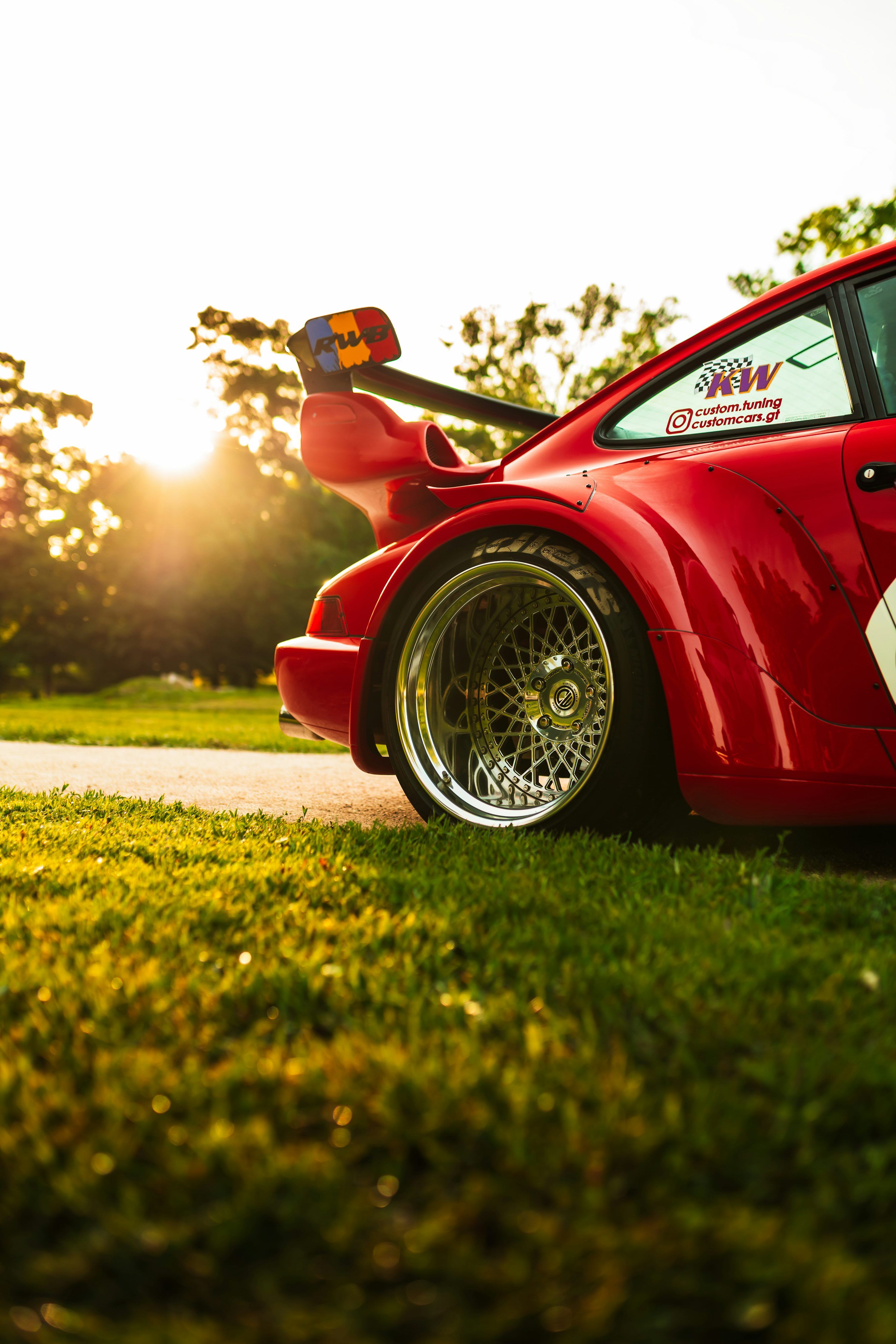 3000x4500 A red sports car with a large spoiler at sunset