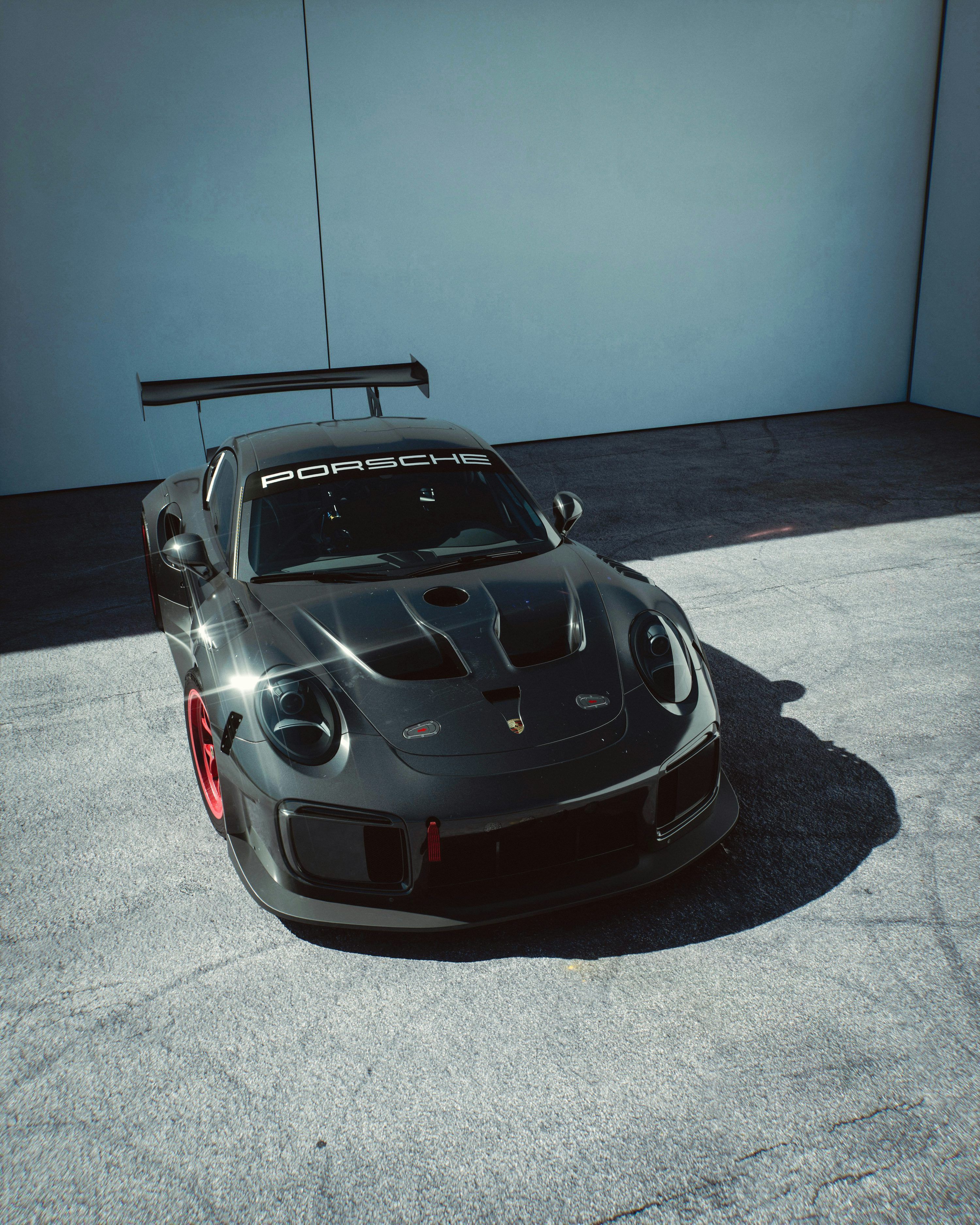 3000x3750 A dark grey porsche gt2 rs with red wheels