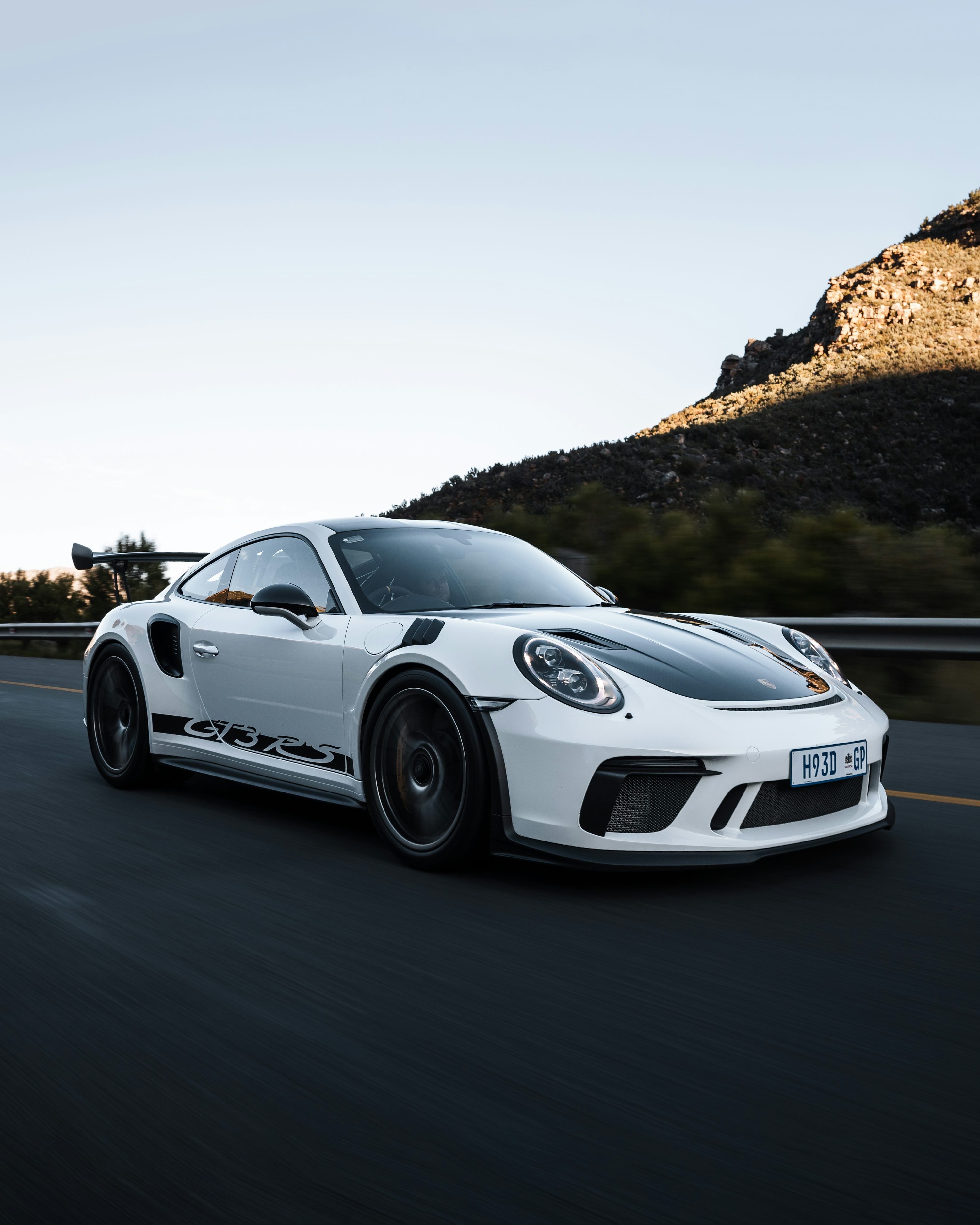 3000x3750 A white porsche sports car driving down a road