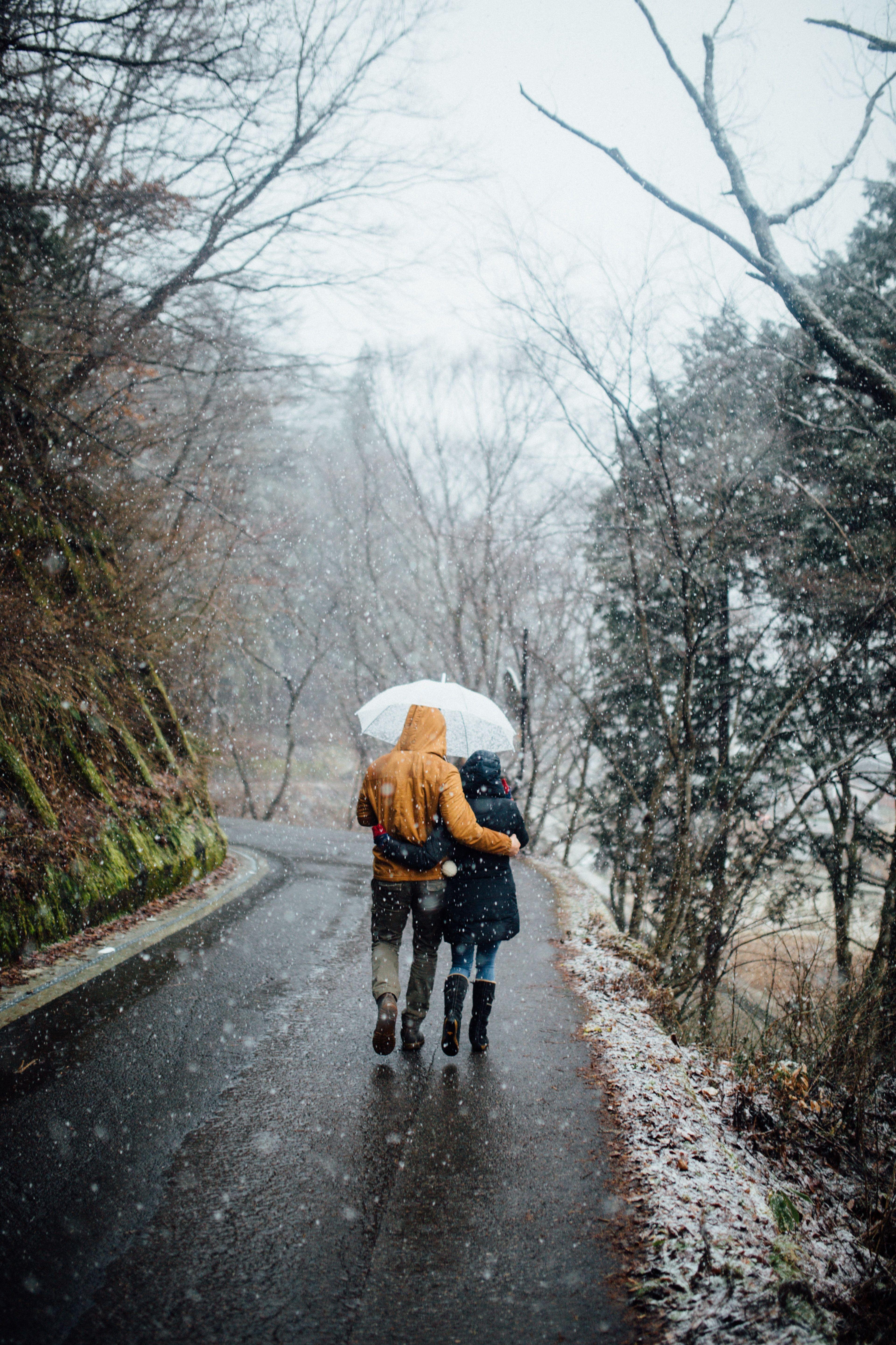 3840x5760 man and woman walking in the rain while holding umbrella photo