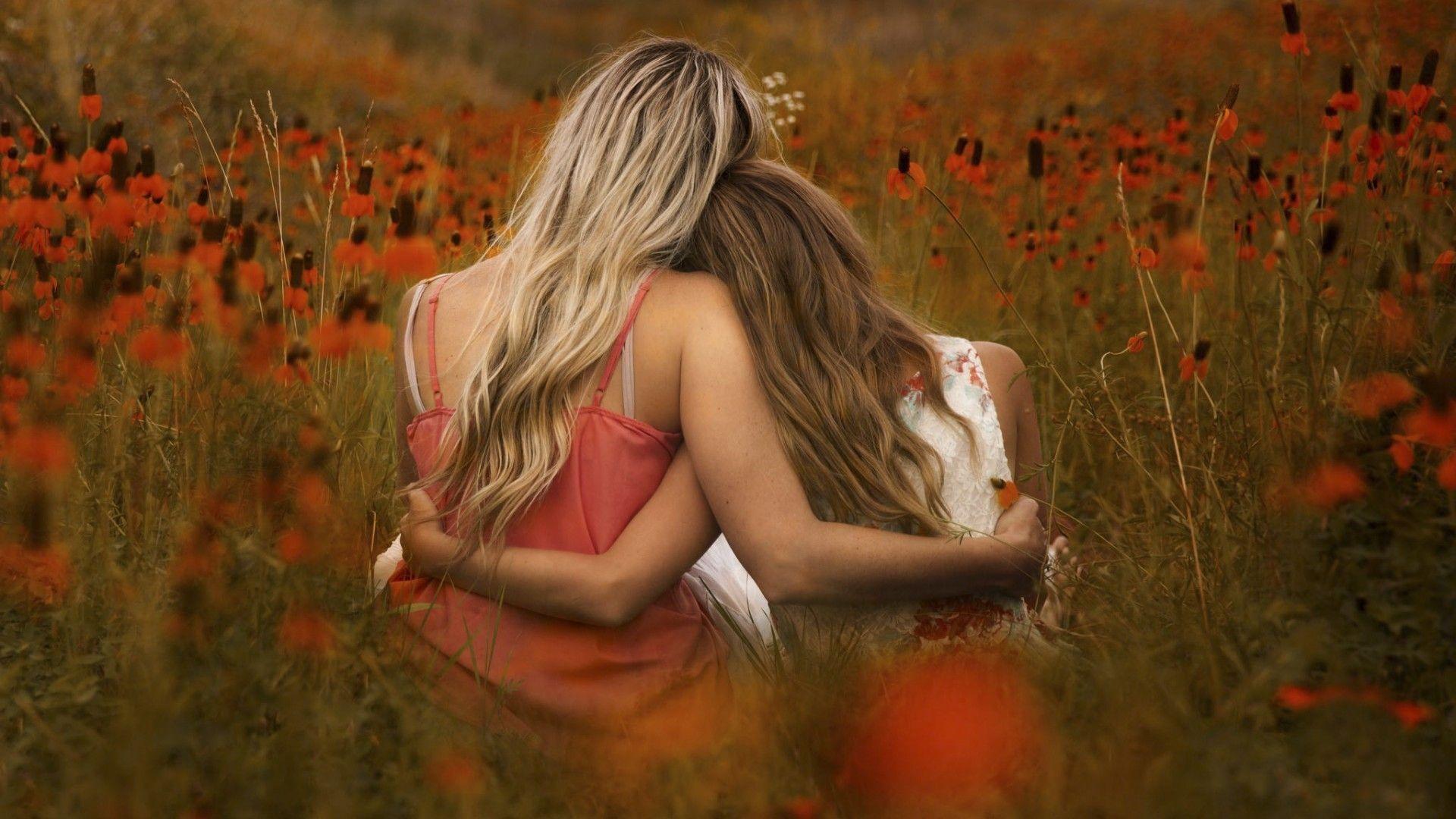 1920x1080 Two girls sit embracing in a field wallpaper and image, picture, photo
