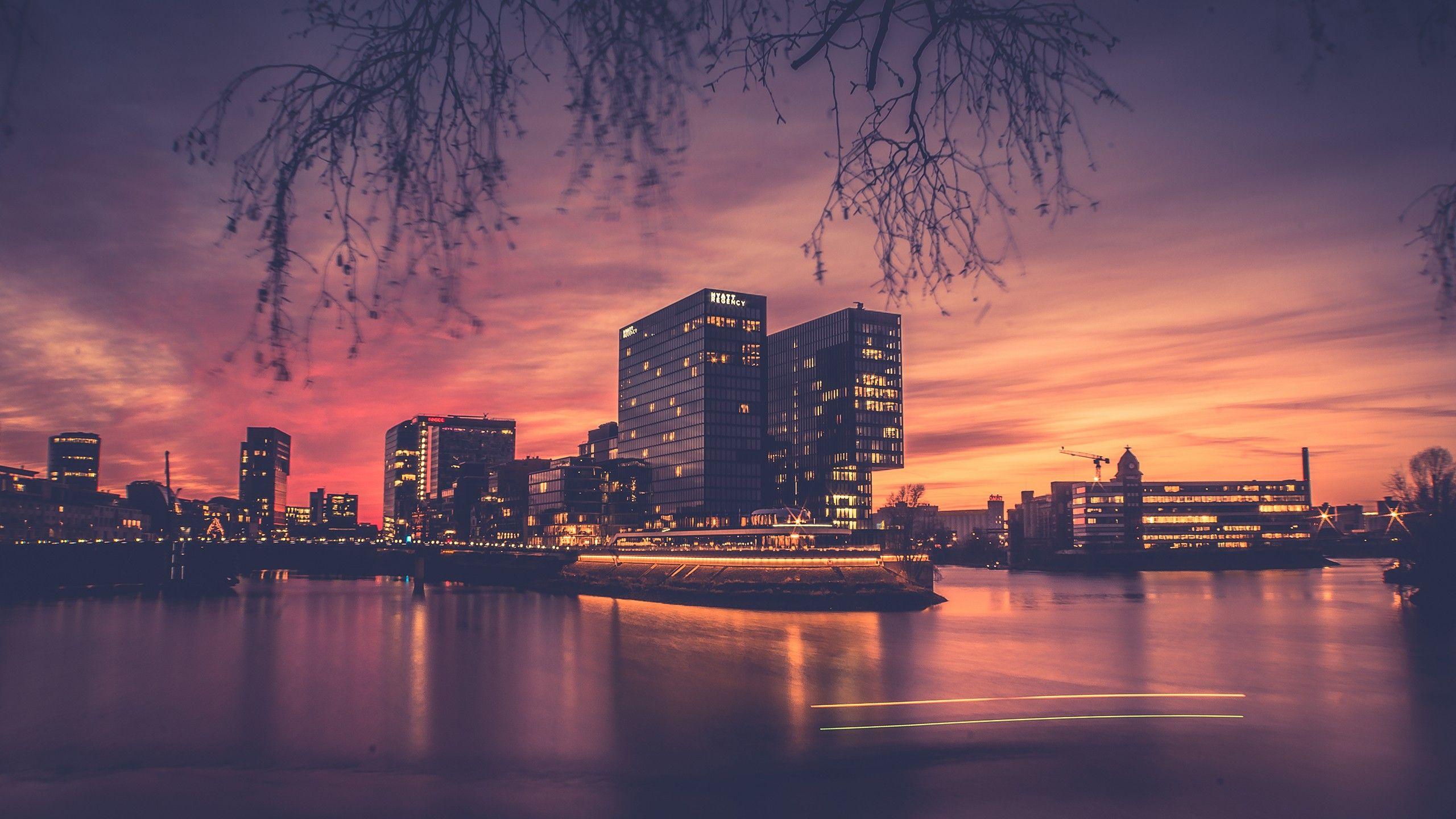 2560x1440 architecture, Building, City, Cityscape, Branch, Trees, Water, Sunset, Light trails, Lights, Reflection, Modern, Long exposure, Clouds, Blurred Wallpaper HD / Desktop and Mobile Background