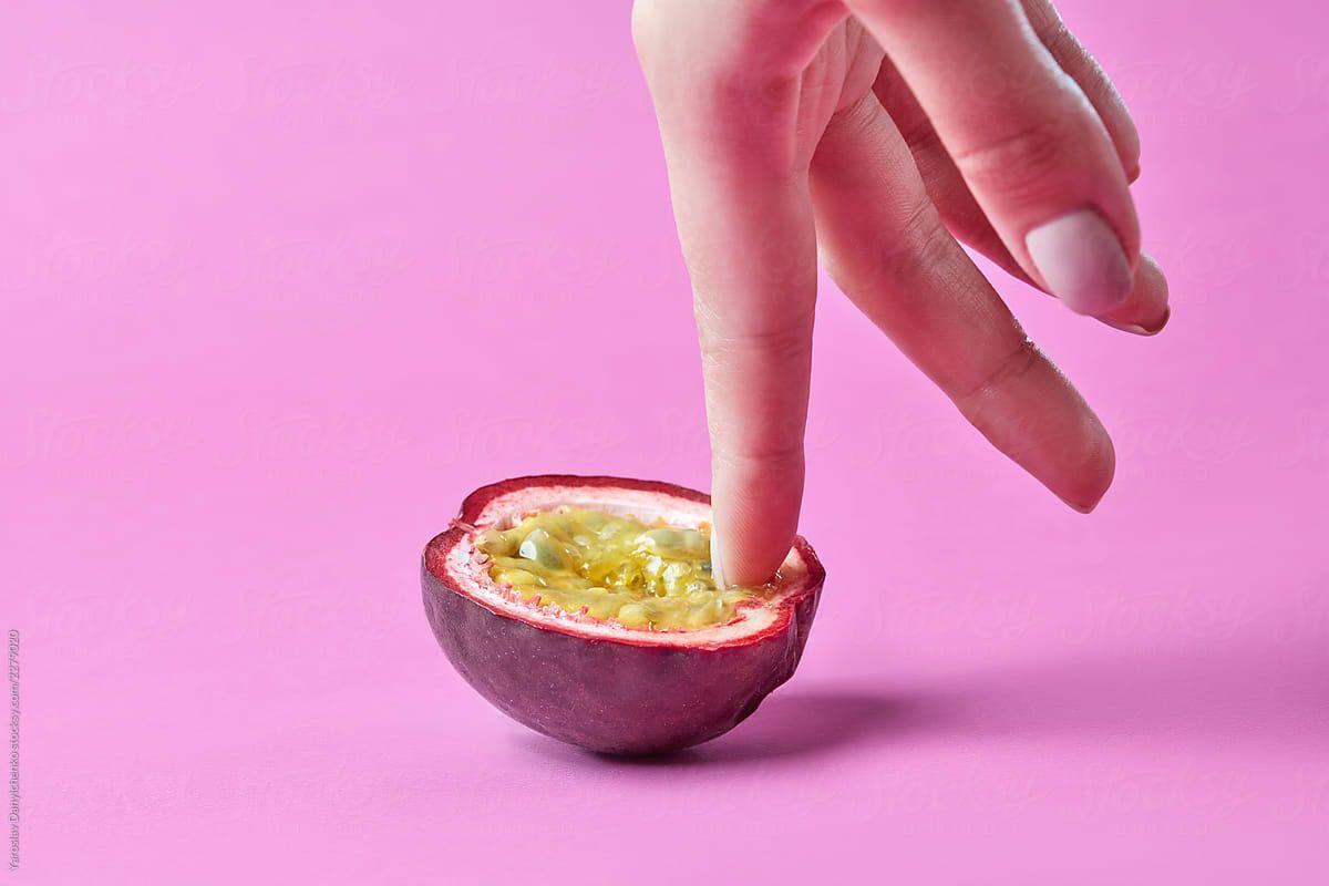 1200x800 Woman's finger touch inside passion exotic fruit on a pink background. Simulation of masturbation, Vagina concept.