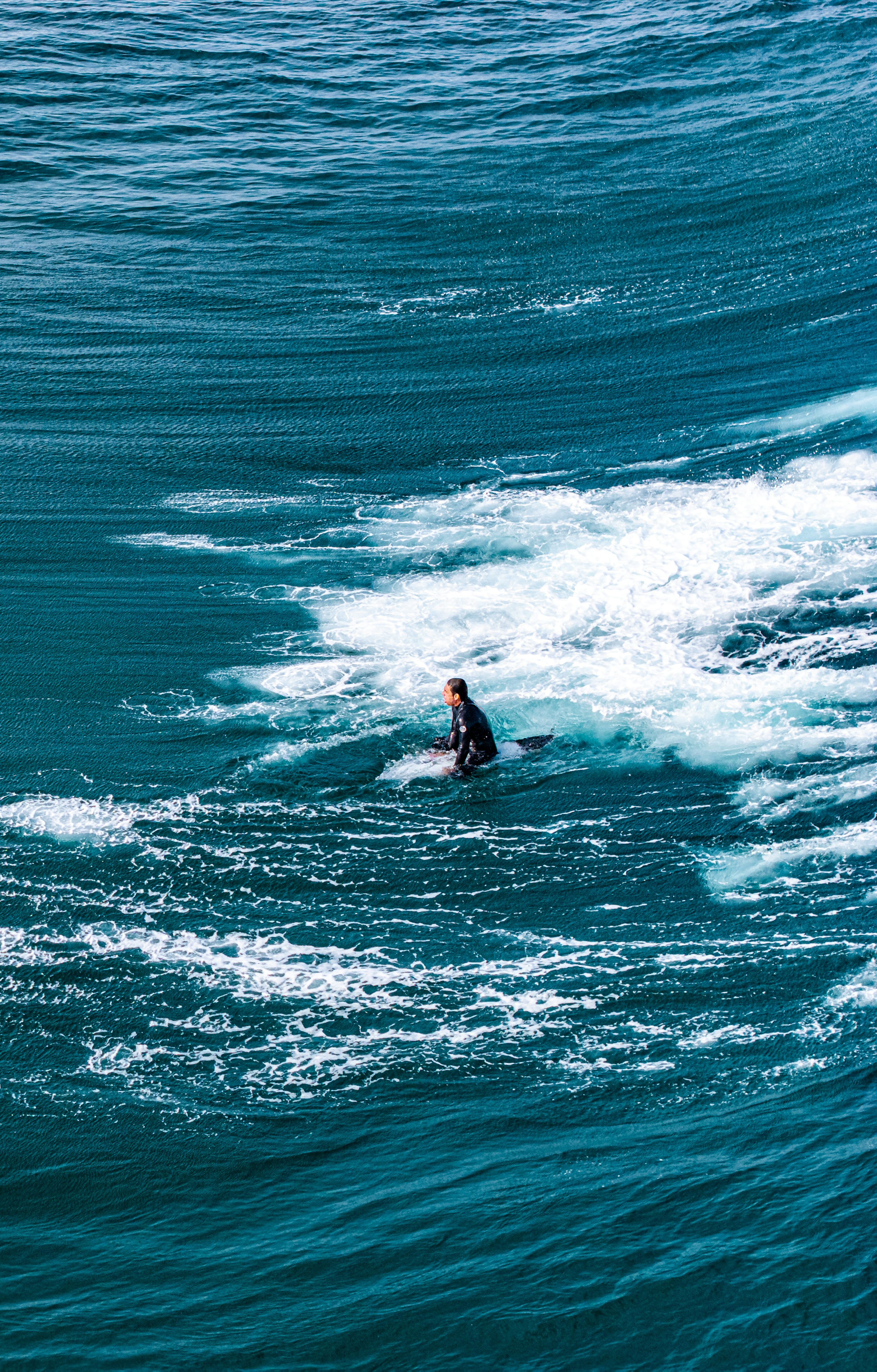 3000x4694 Surfer paddling through deep blue ocean waves