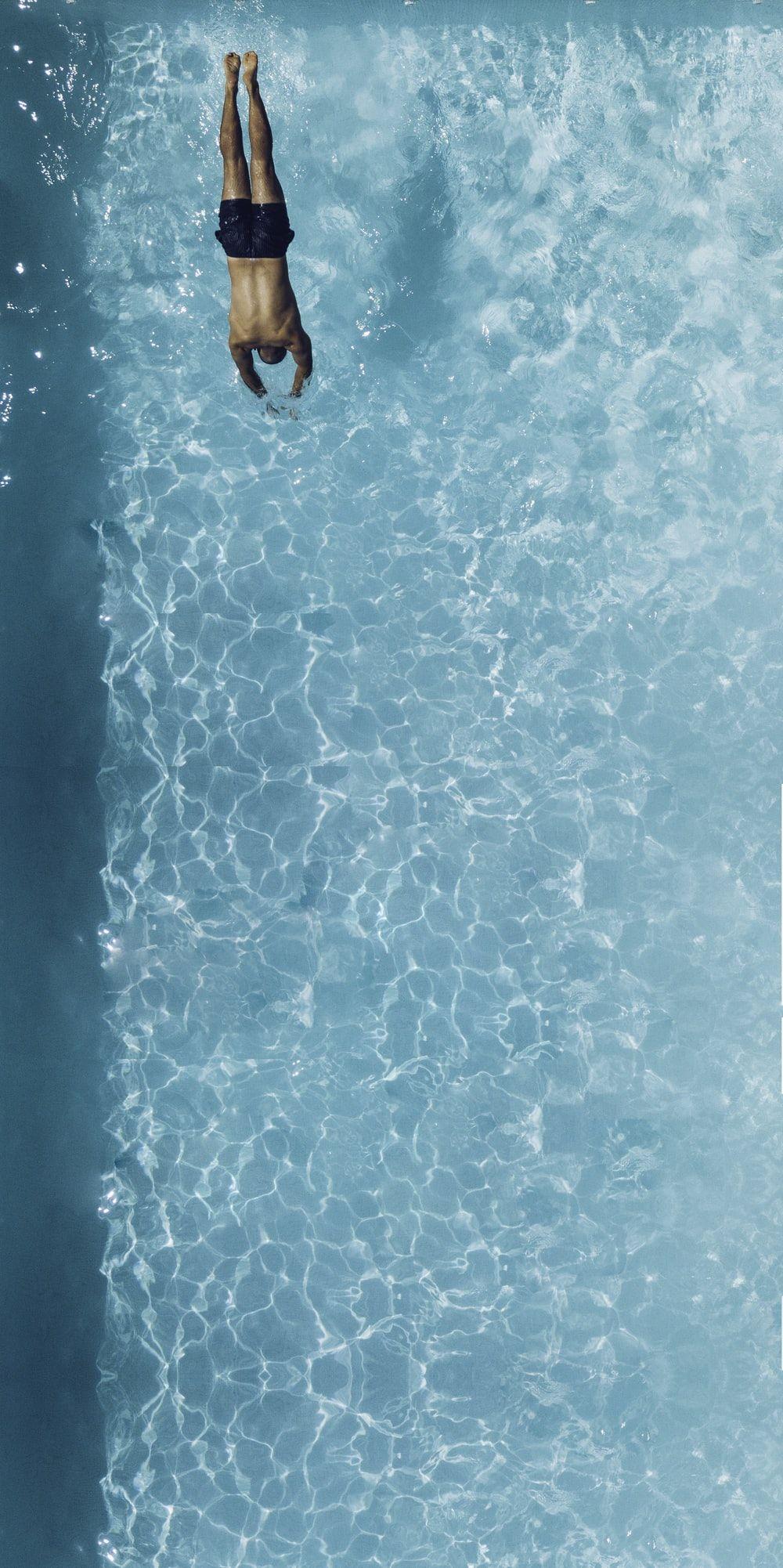 1000x2002 man falling on blue body of water photo
