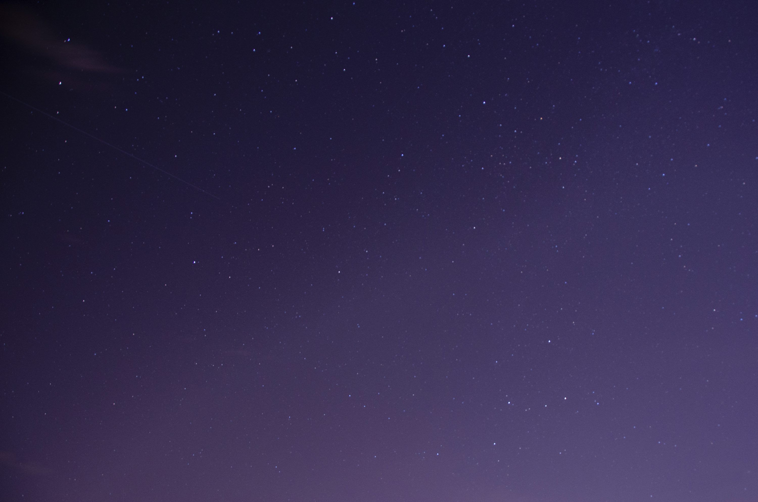 3000x1987 A night sky with stars and a plane in the distance
