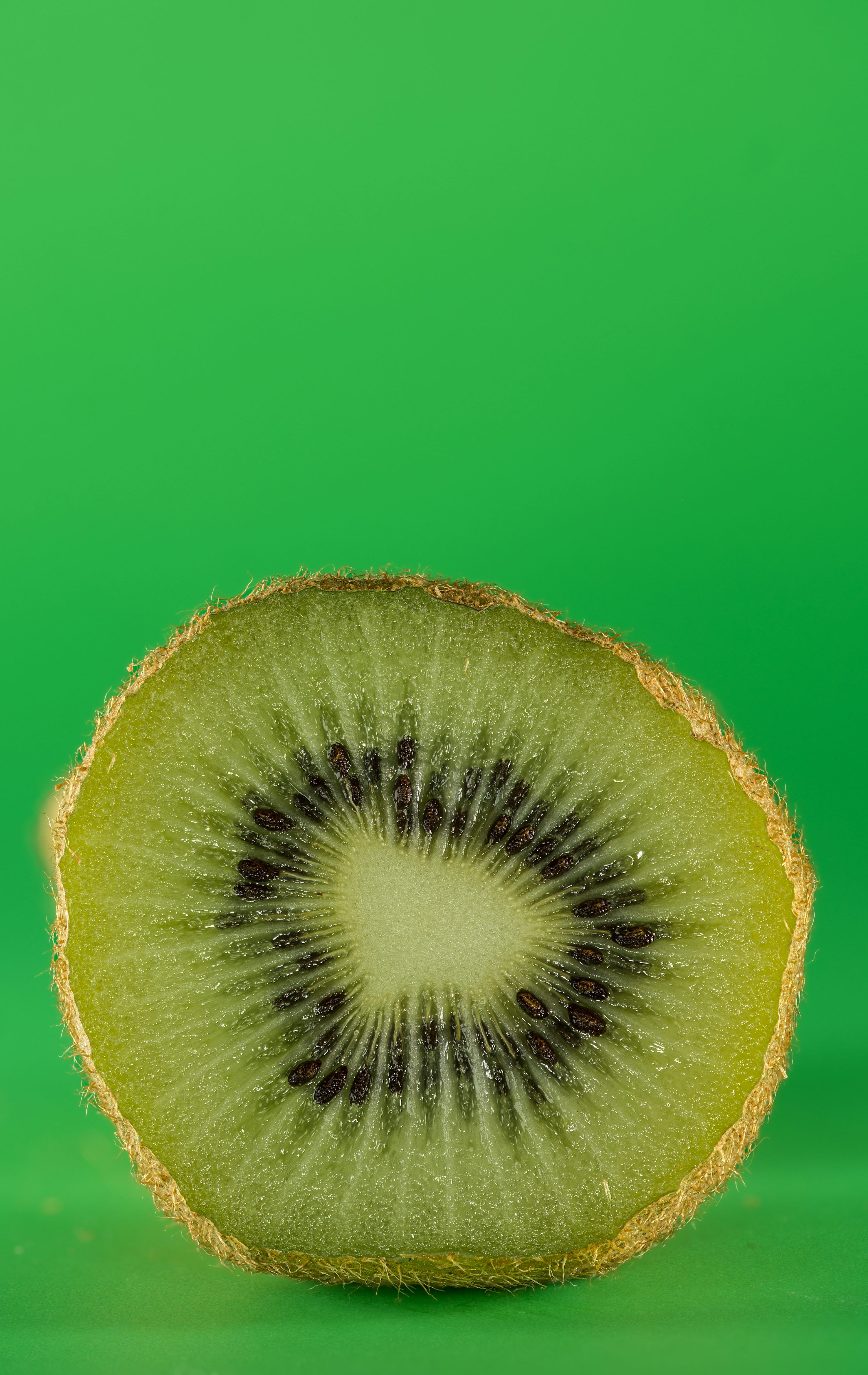 3000x4749 A kiwi cut in half on a green background