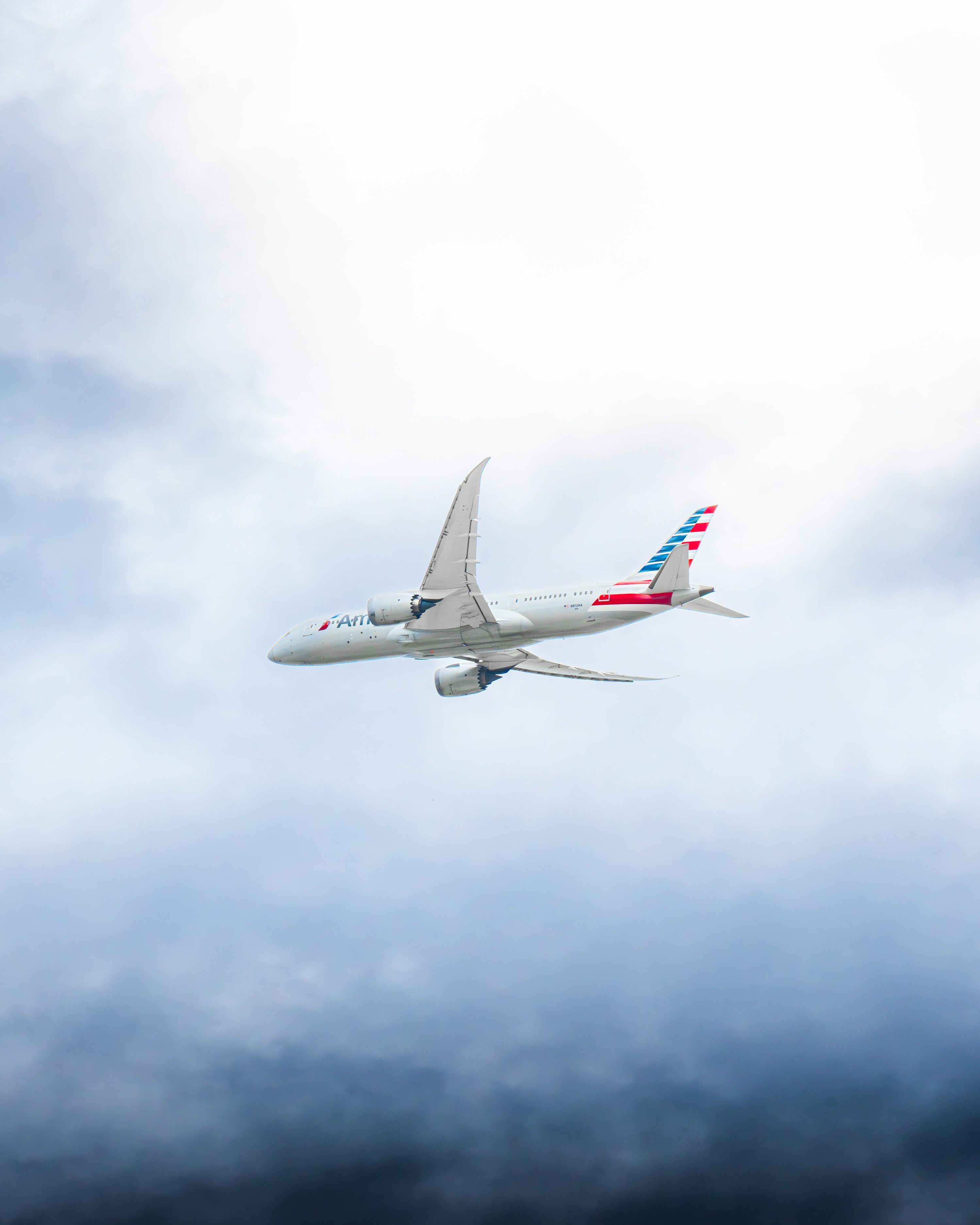 3000x3750 A commercial airplane flying through cloudy skies