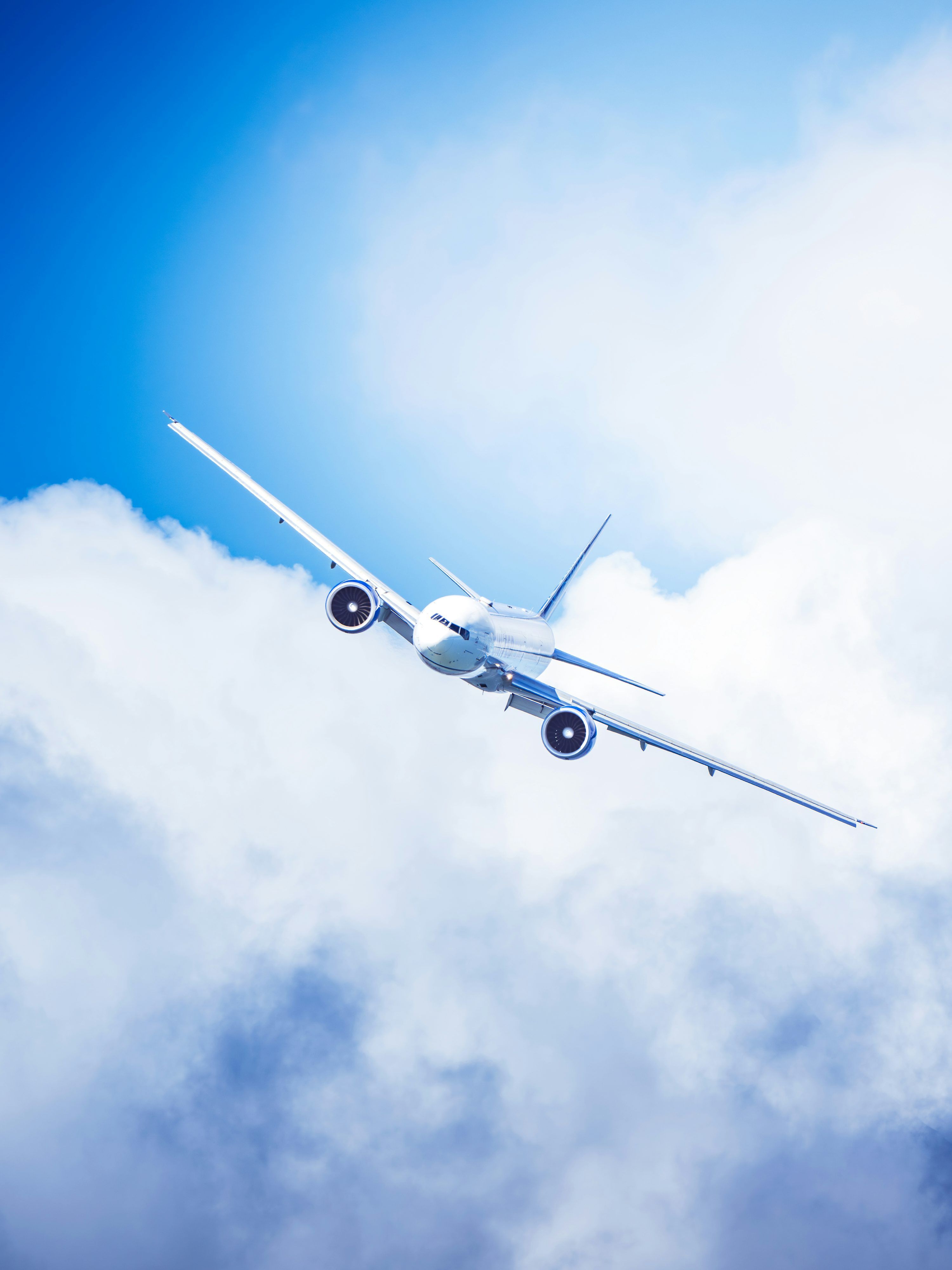 3000x4000 A commercial airplane flying through fluffy clouds