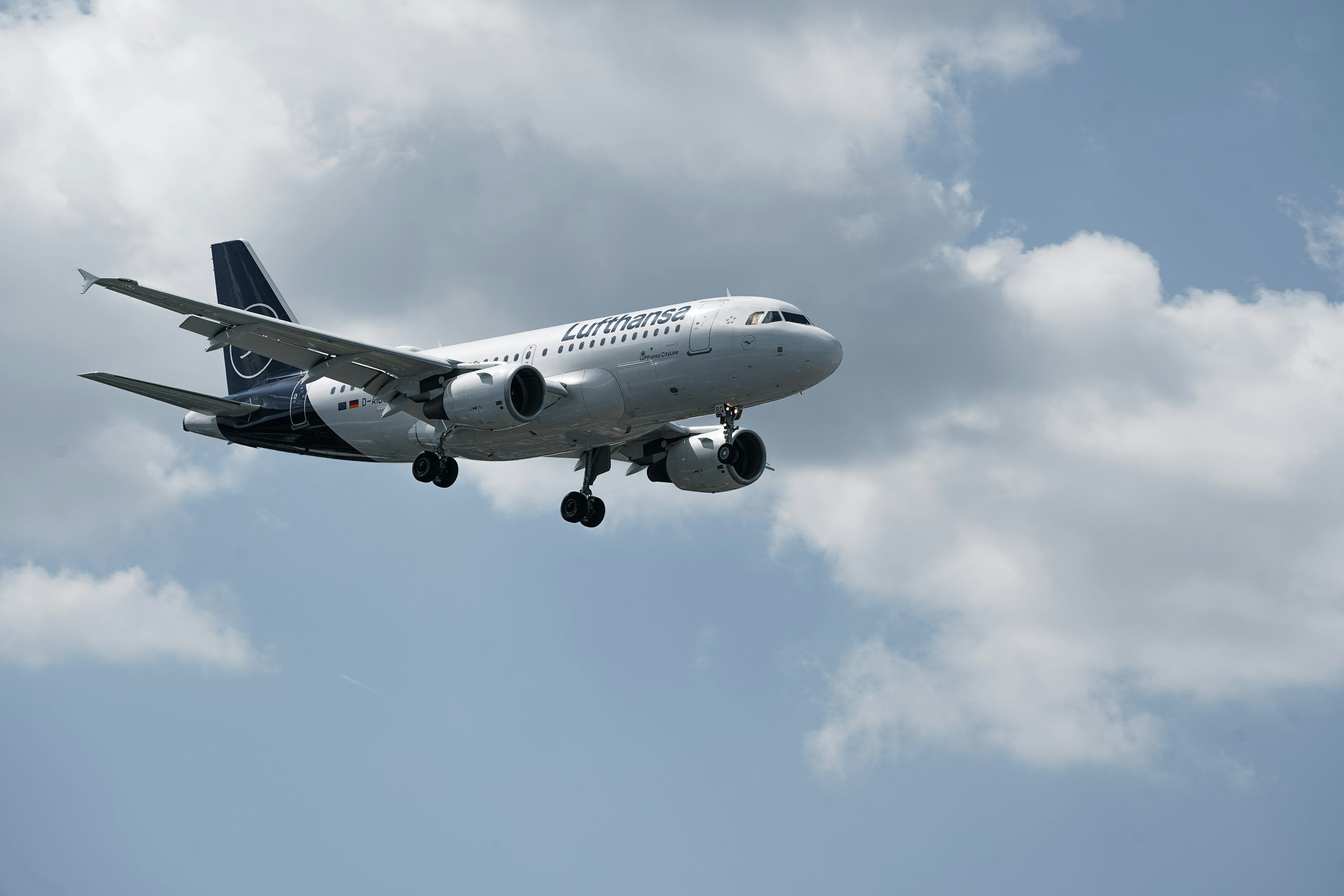 3000x2000 Commercial airplane descending with landing gear extended under cloudy sky. photo