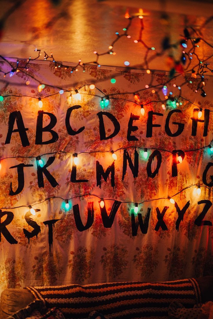 736x1102 Stranger Things party decorations / Byers living room. “Wallpaper” diy using a floral sheet and iron on letters printed from the computer onto dark fabric transfer paper. Christmas lights plugged into a