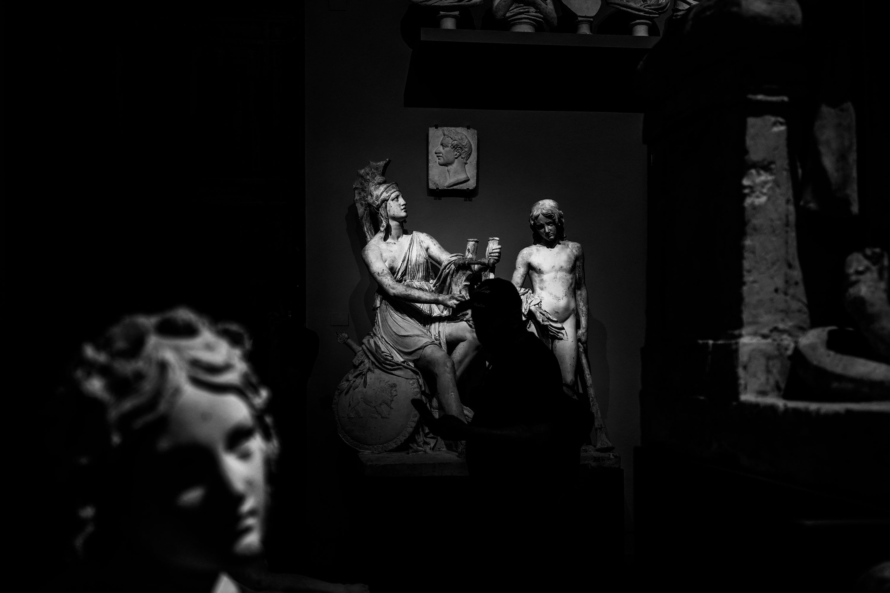 3000x2000 Ancient sculptures illuminated by dramatic spotlight in dark museum