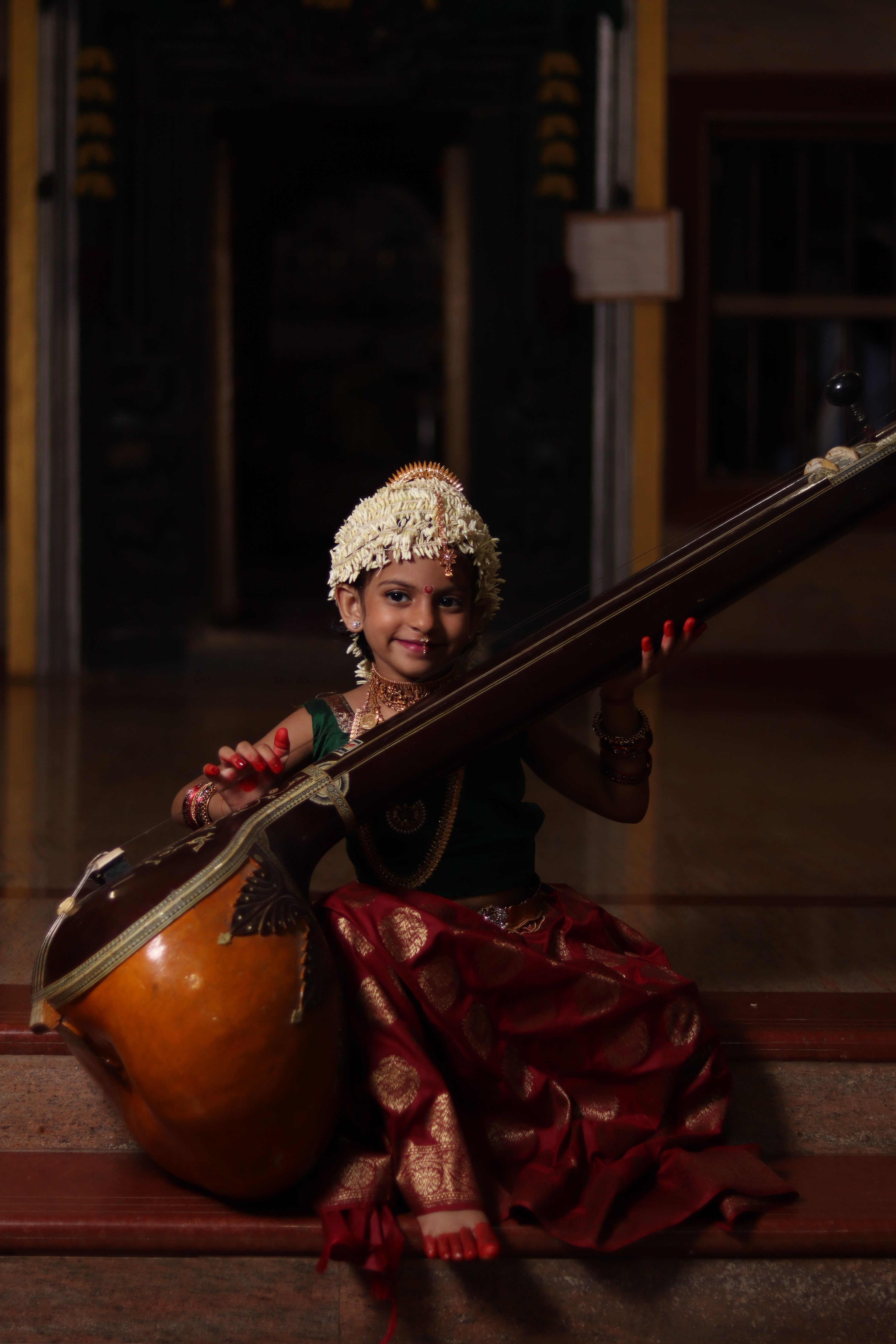 3899x5847 Smiling Girl Sitting on Concrete Stairs Playing Tanpura Instrument · Free