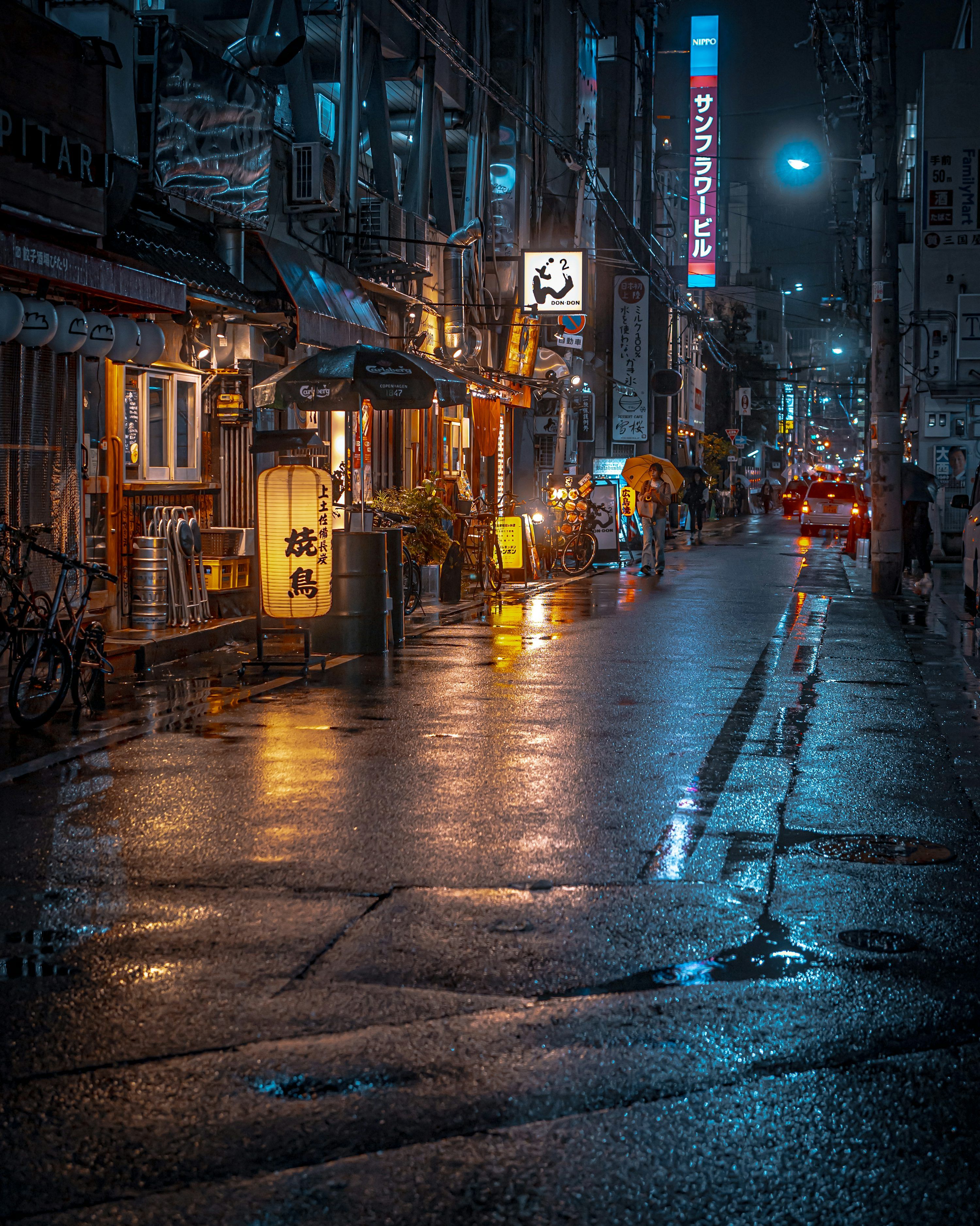3000x3750 A wet city street at night with cars parked on the side of the road