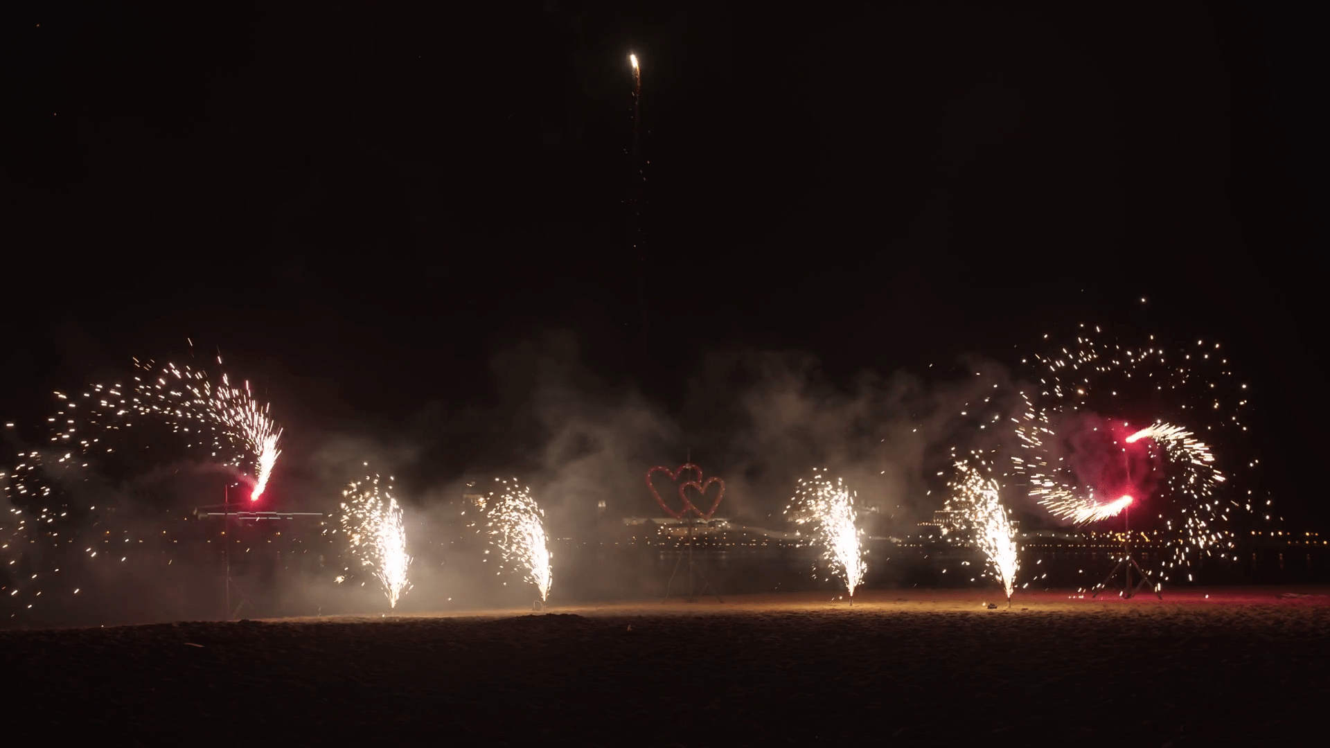 1920x1080 Exploding and spinning fireworks on the beach and burning stand in hearts shape Stock Video Footage
