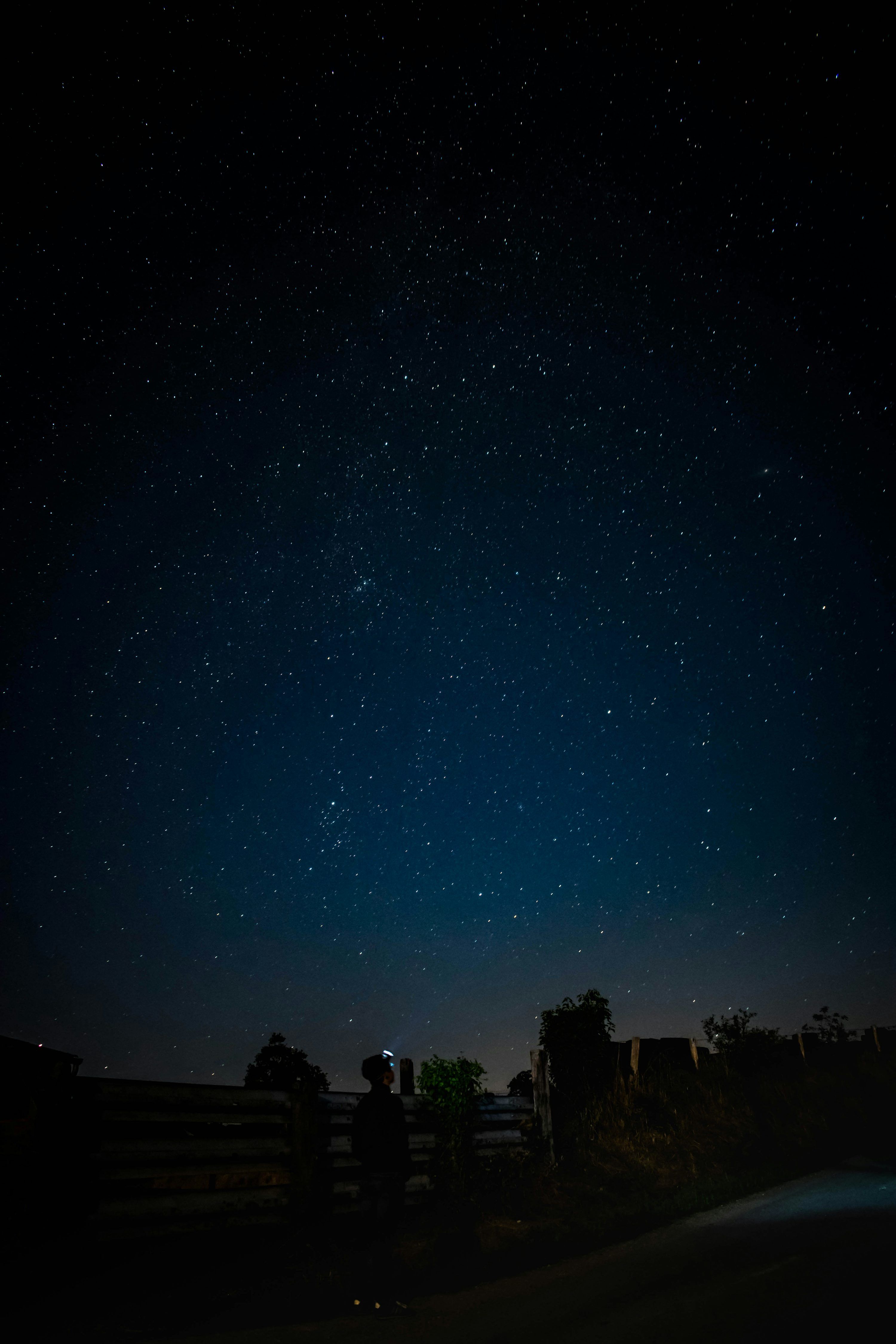 3000x4500 Man standing near fence watching stars during night time