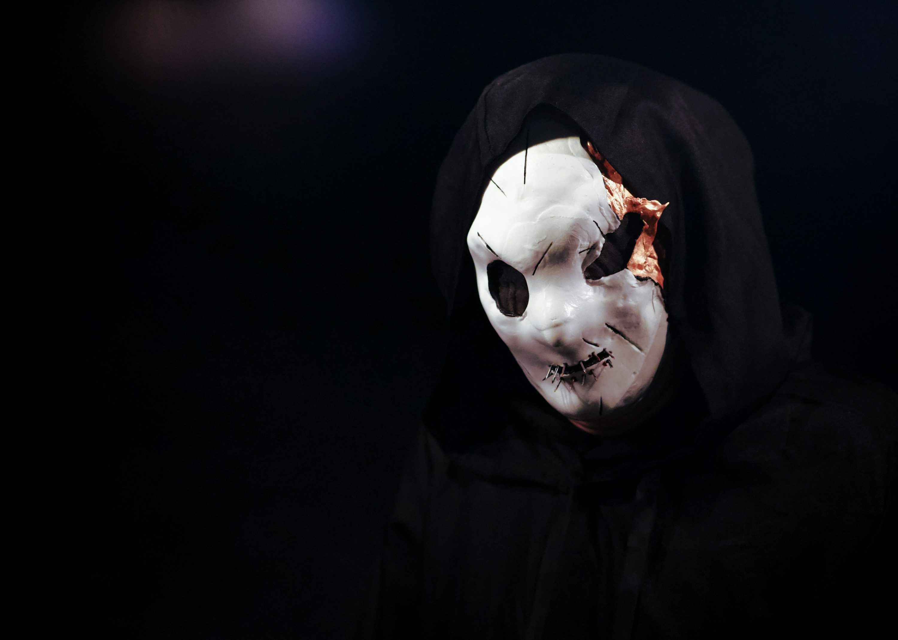 3000x2139 A person wearing a white mask and a black hood
