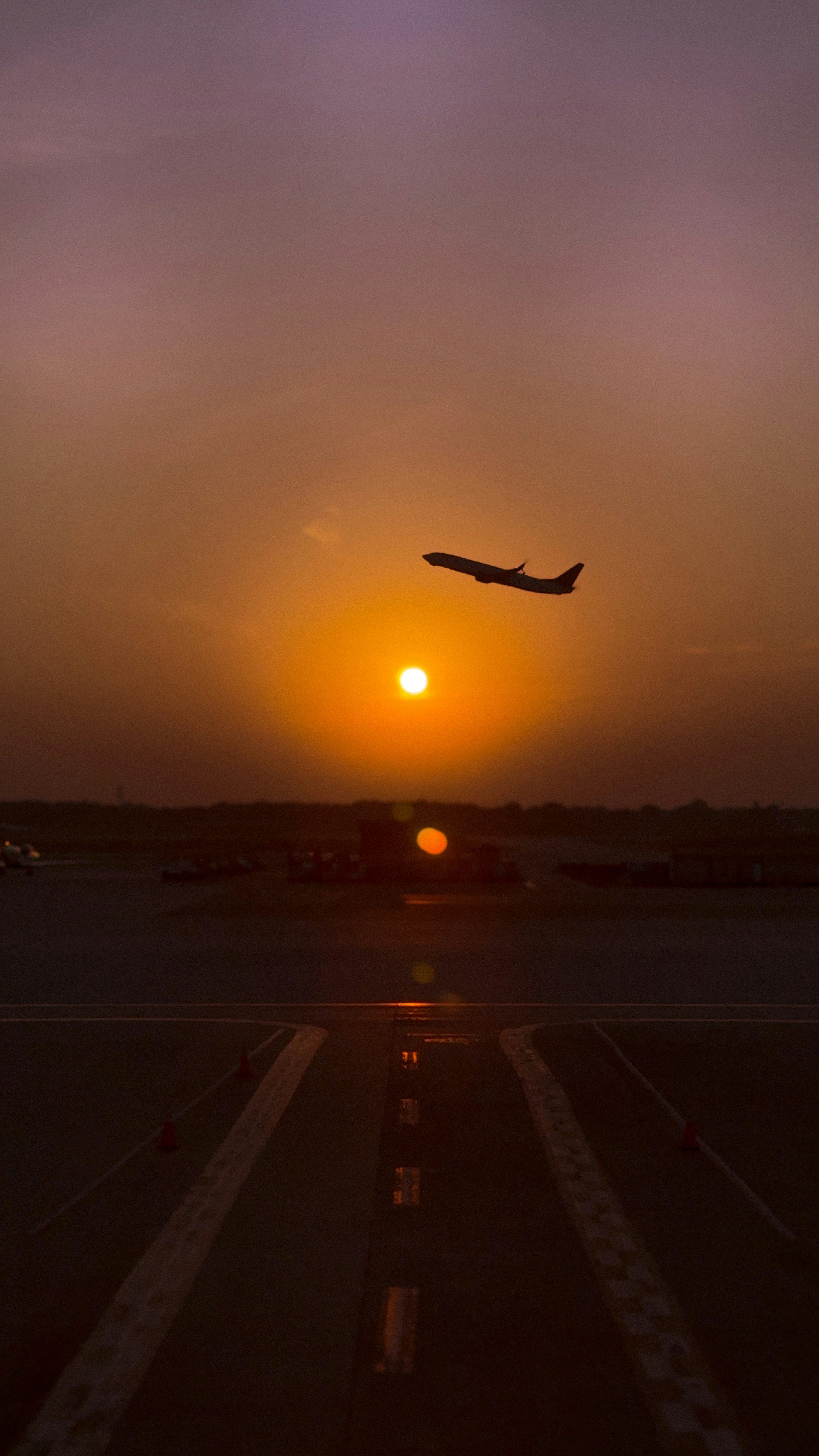 3000x5332 An airplane is taking off into a sunset