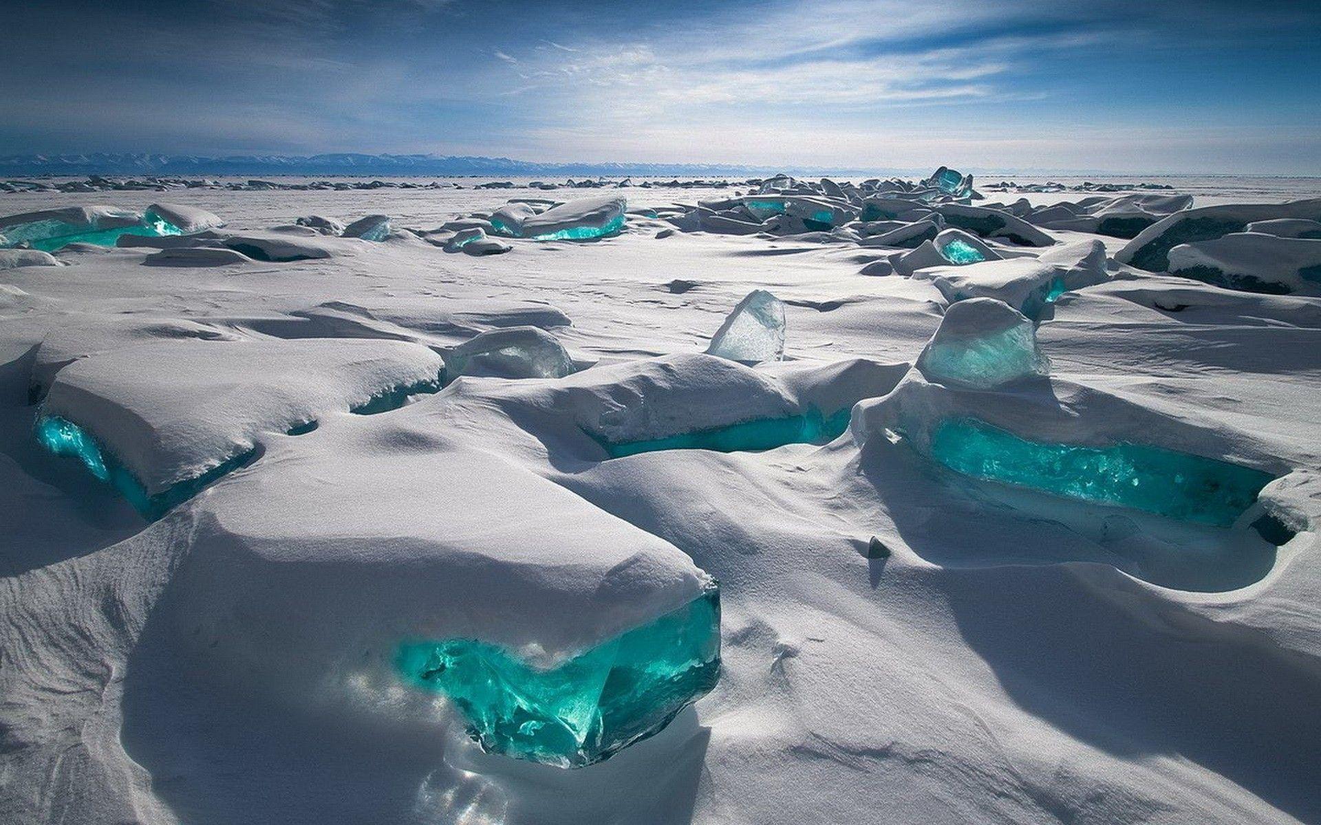 White snow field with large strikingly blue ice cubes pocking through. This is photo of Siberian environment of crispy clean air and land without toxins. Using products grown and manufactured in clean environments like that ensures their high quality and purity.