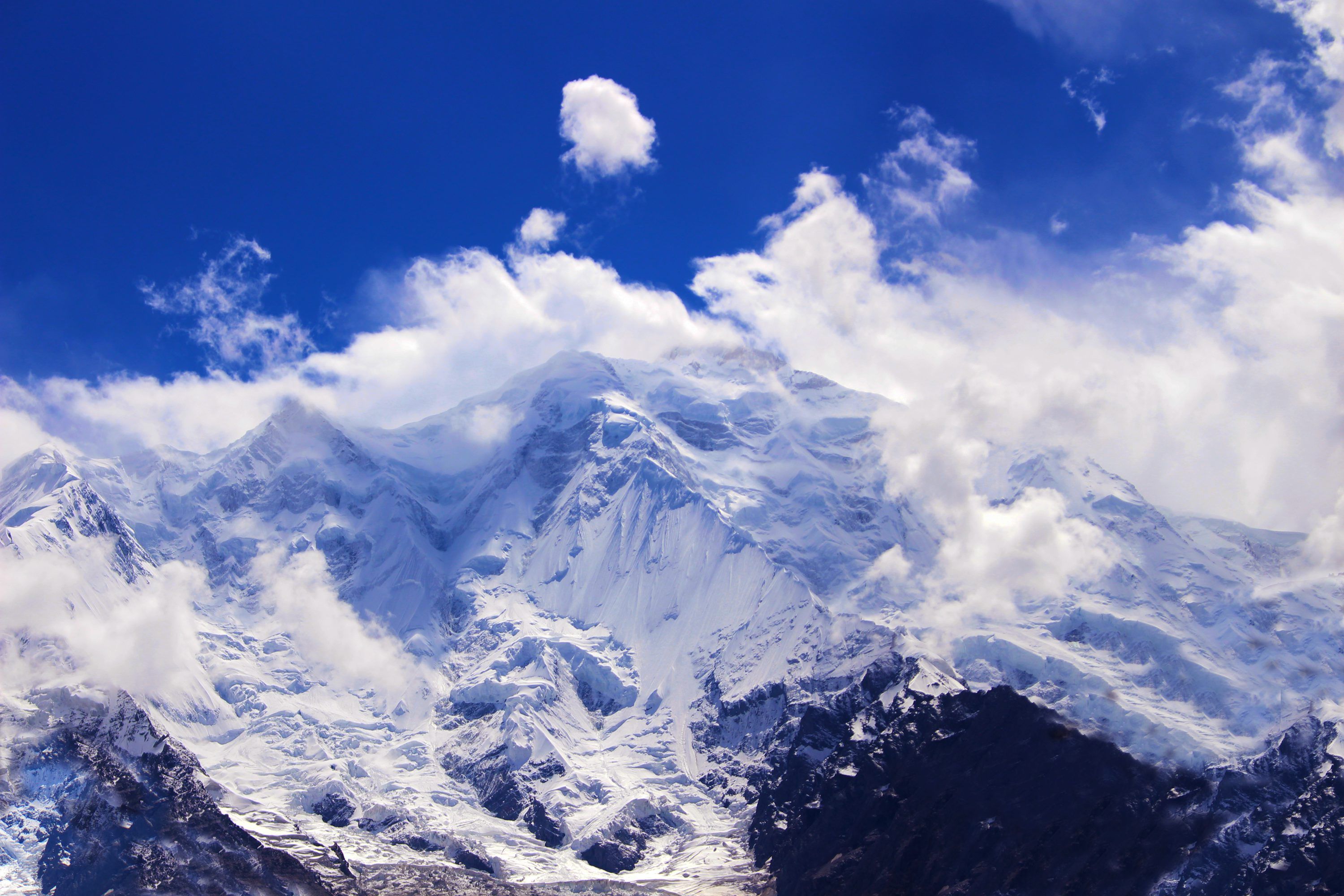 3000x2000 A snow covered mountain range under a partly cloudy sky