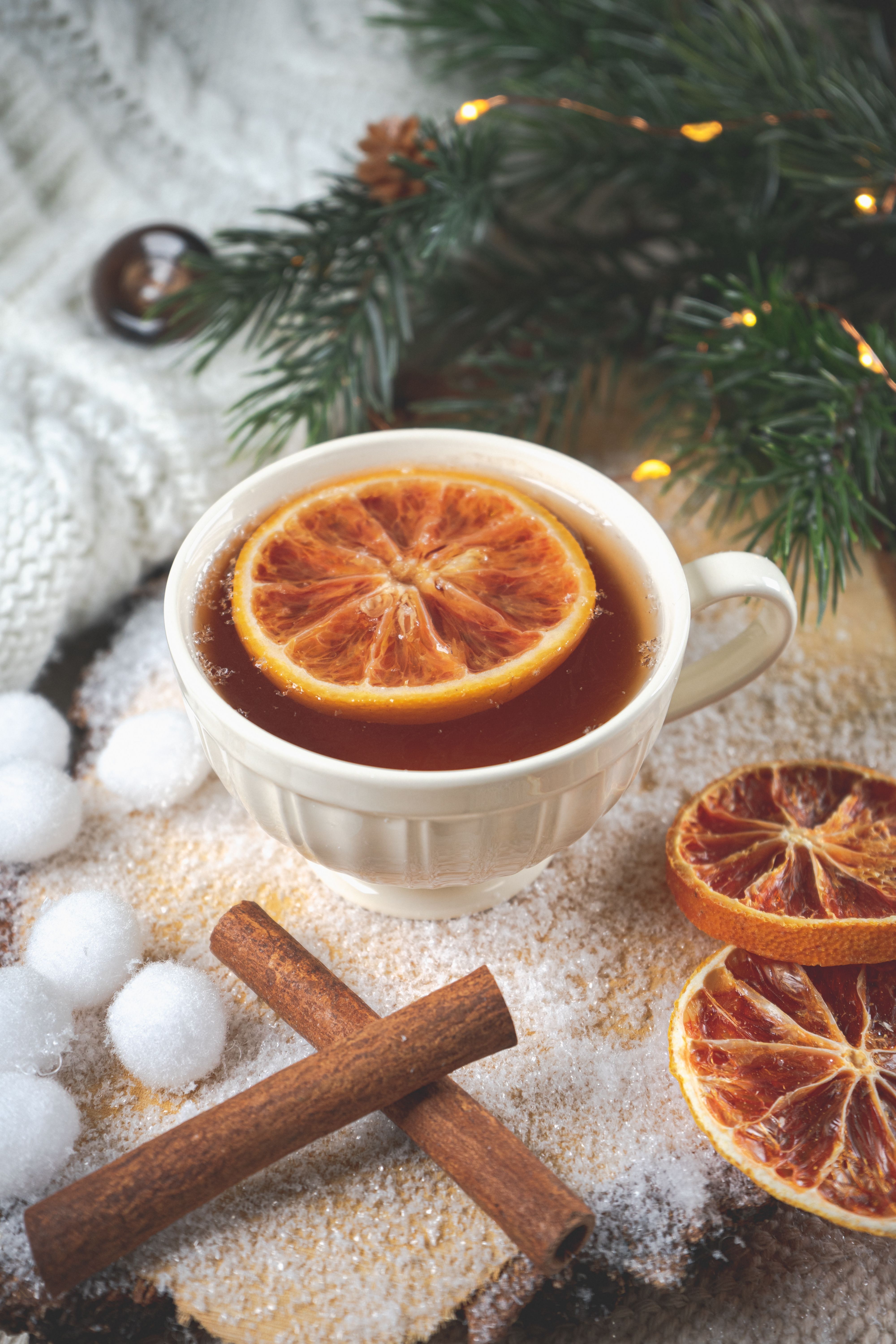 4000x6000 A Cup of Tea with a Slice of Orange and Cinnamon Sticks and Christmas Decorations Lying Around · Free