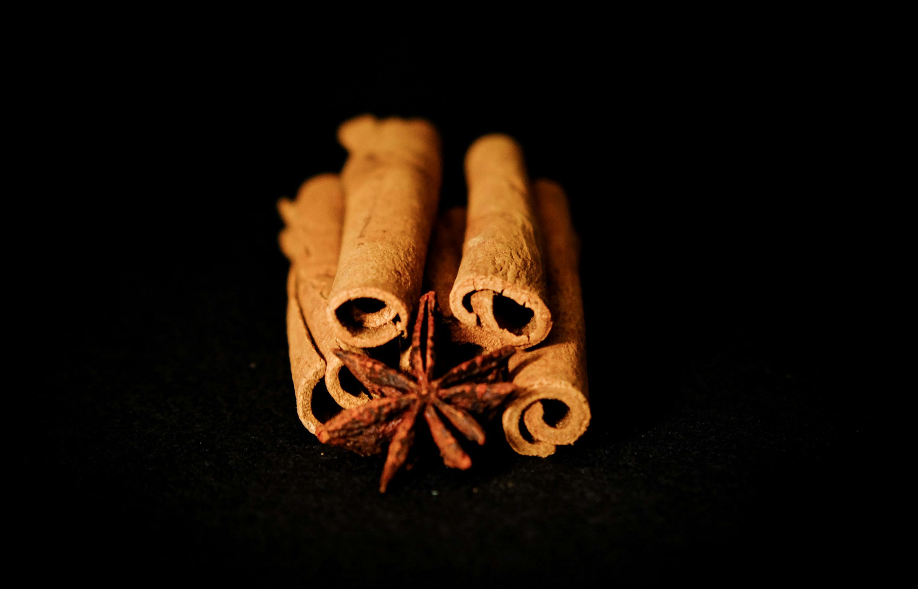 3000x1925 A bowl of cinnamon sticks next to a pile of cinnamon sticks