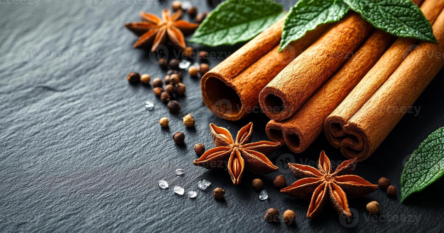 1862x980 Spices and herbs on dark surface. Cinnamon sticks, star anise, and mint leaves are beautifully arranged on dark slate, enhancing texture